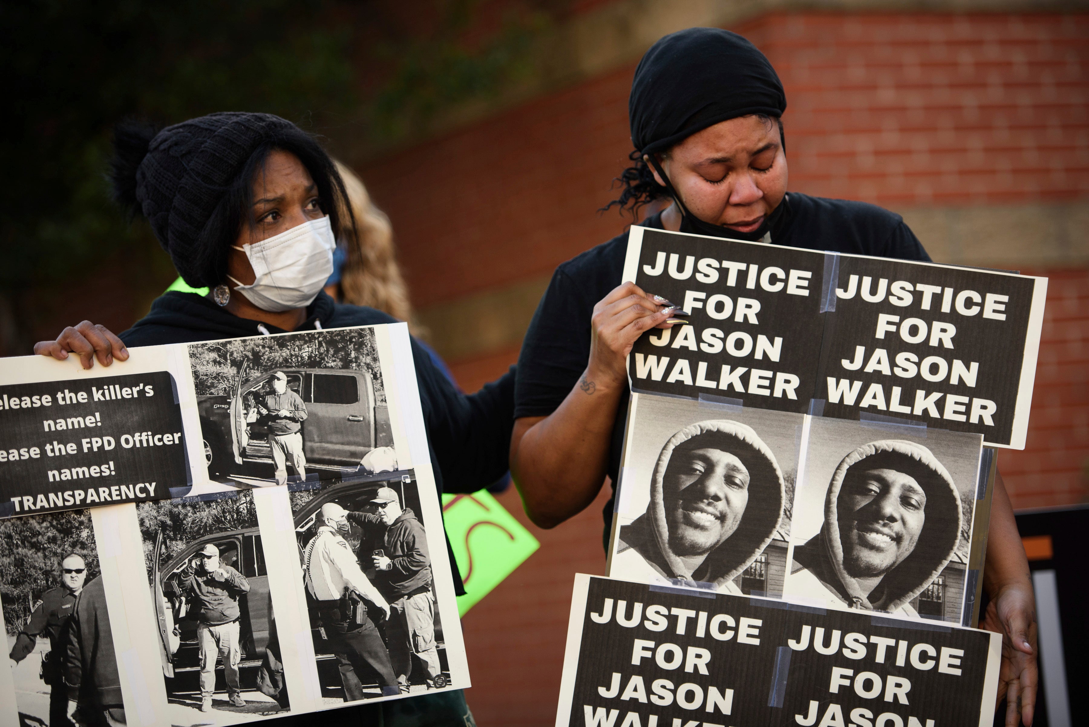Manifestantes sostienen carteles con una foto de Jason Walker durante una protesta frente al Departamento de Policía de Fayetteville el domingo