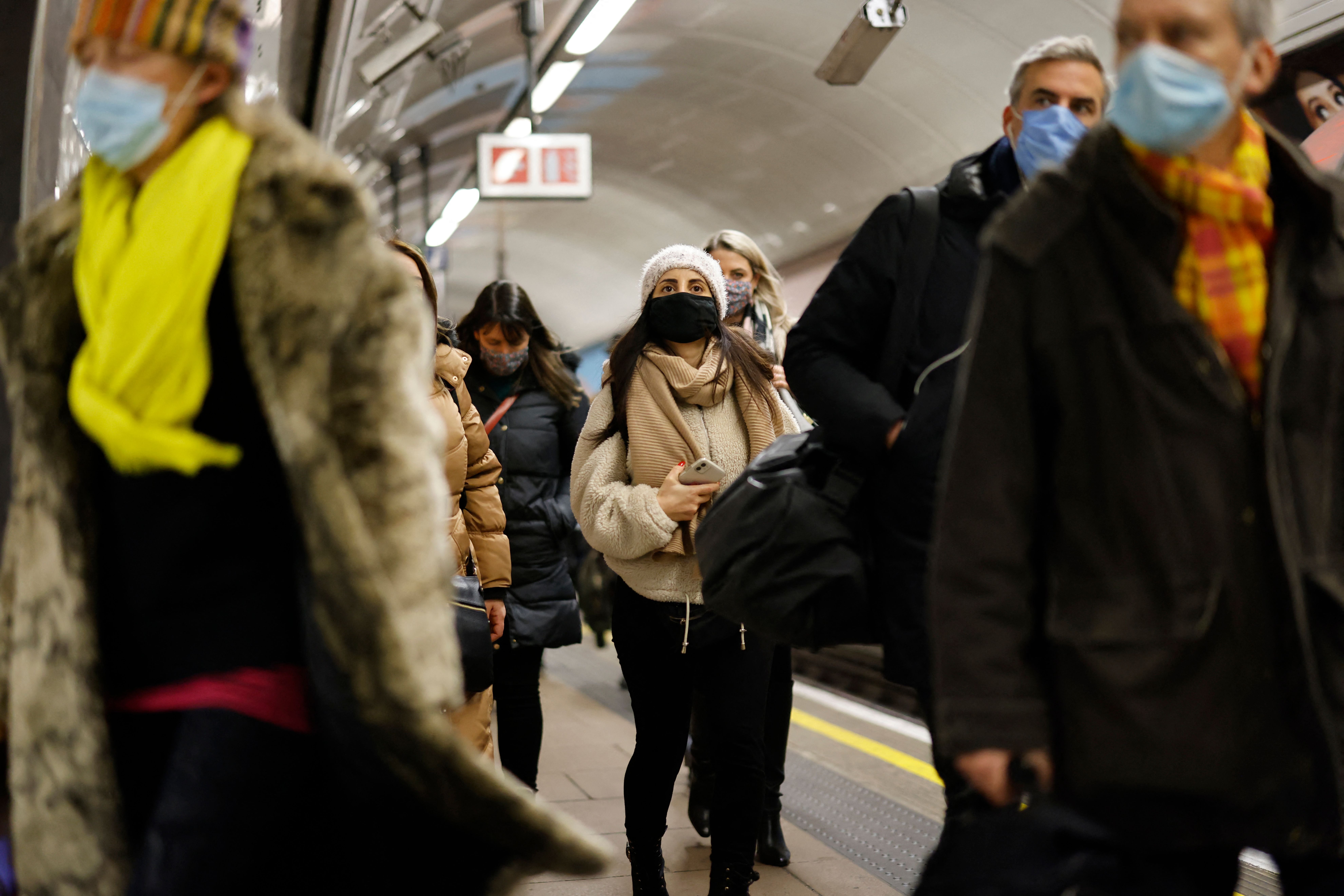 Usuarios del transporte público que llevan cubrebocas salen de una estación del metro en Londres el 21 de enero de 2022