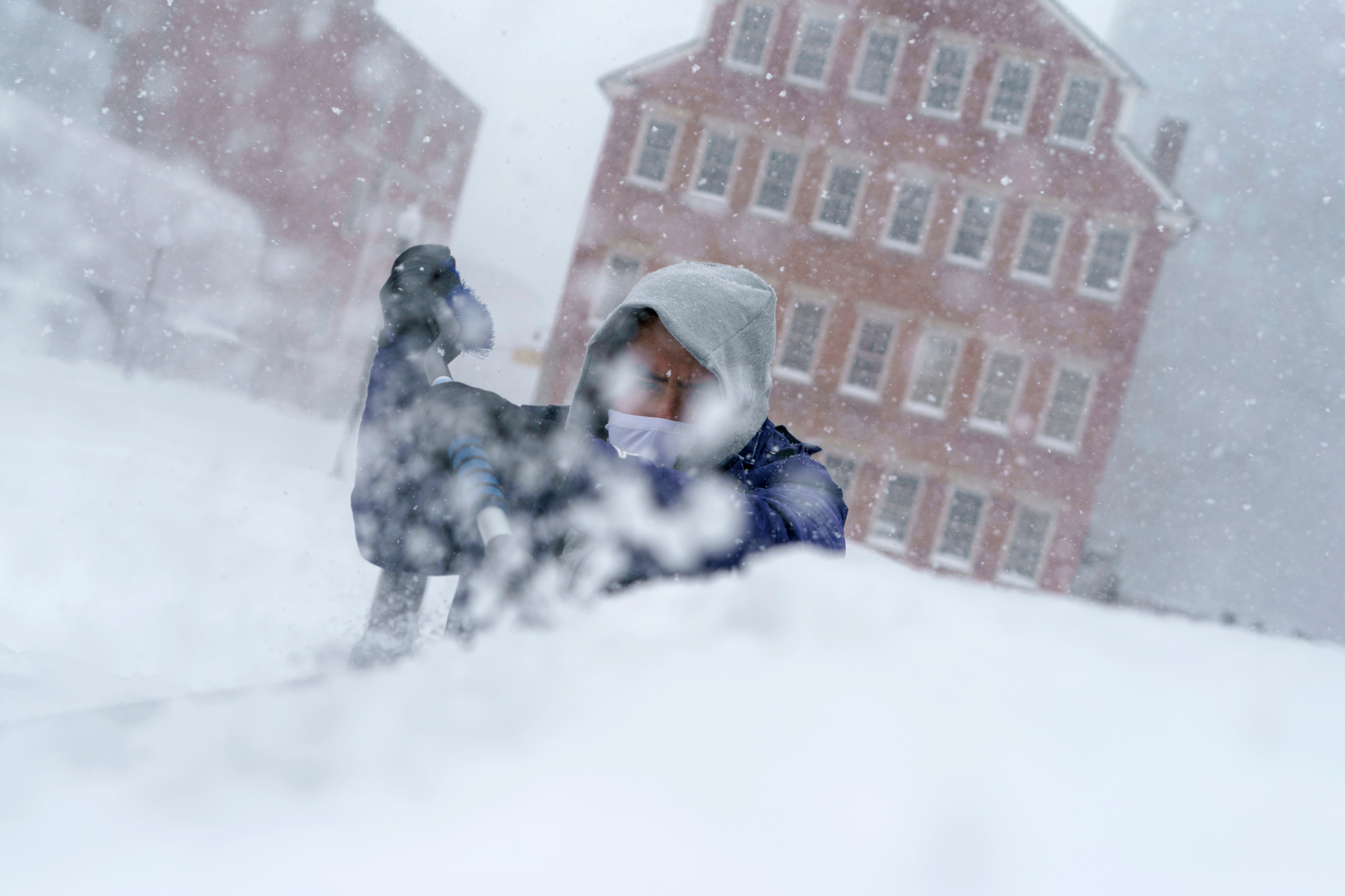 Xavier Martínez raspa la nieve de su parabrisas durante una tormenta en Providence, RI, el 29 de enero de 2022