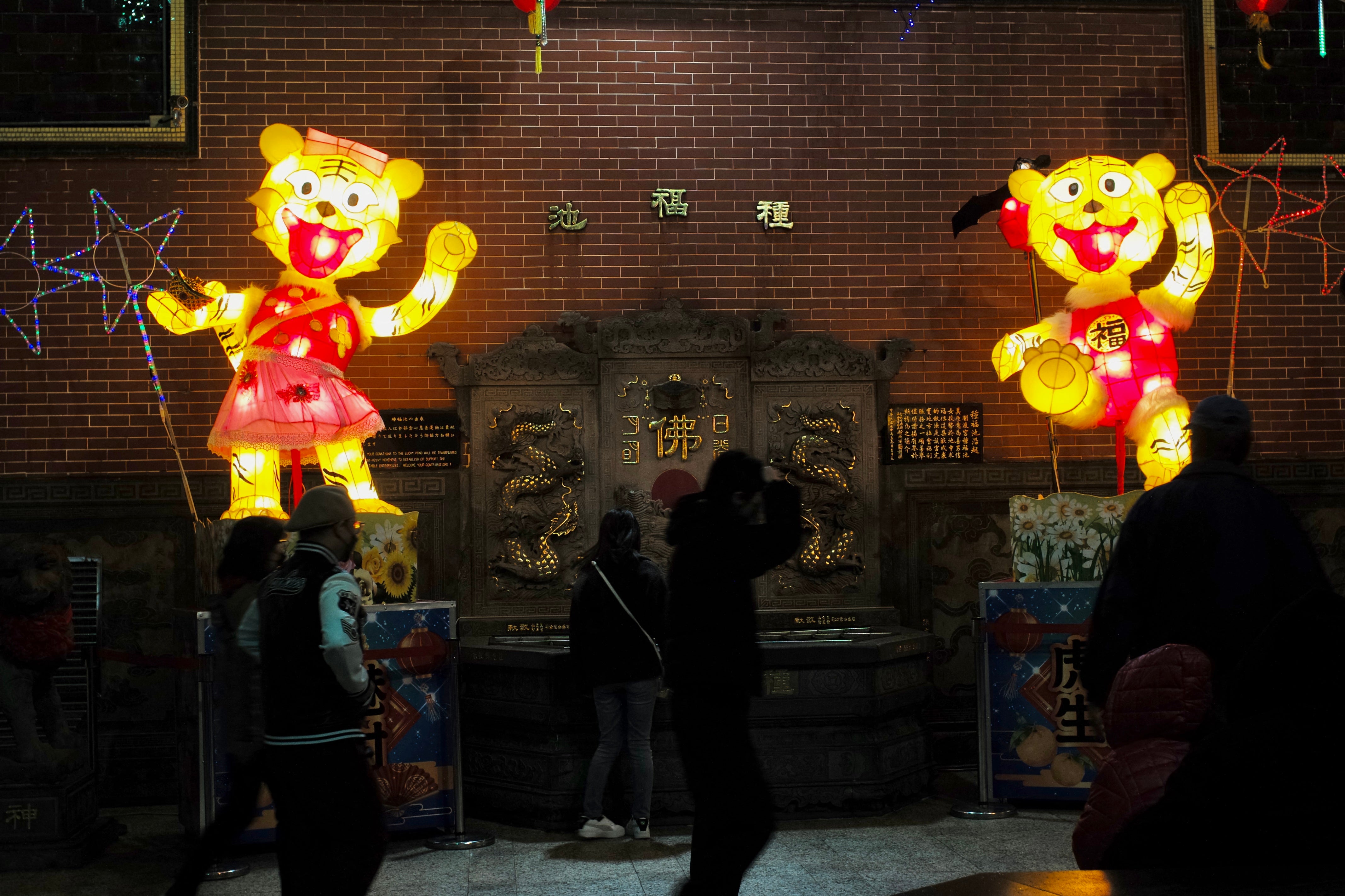 Local residents walk past the tiger lanterns at Taoist Guandu temple on the eve of the Lunar New Year ushering in the Year of the Tiger in Taipei