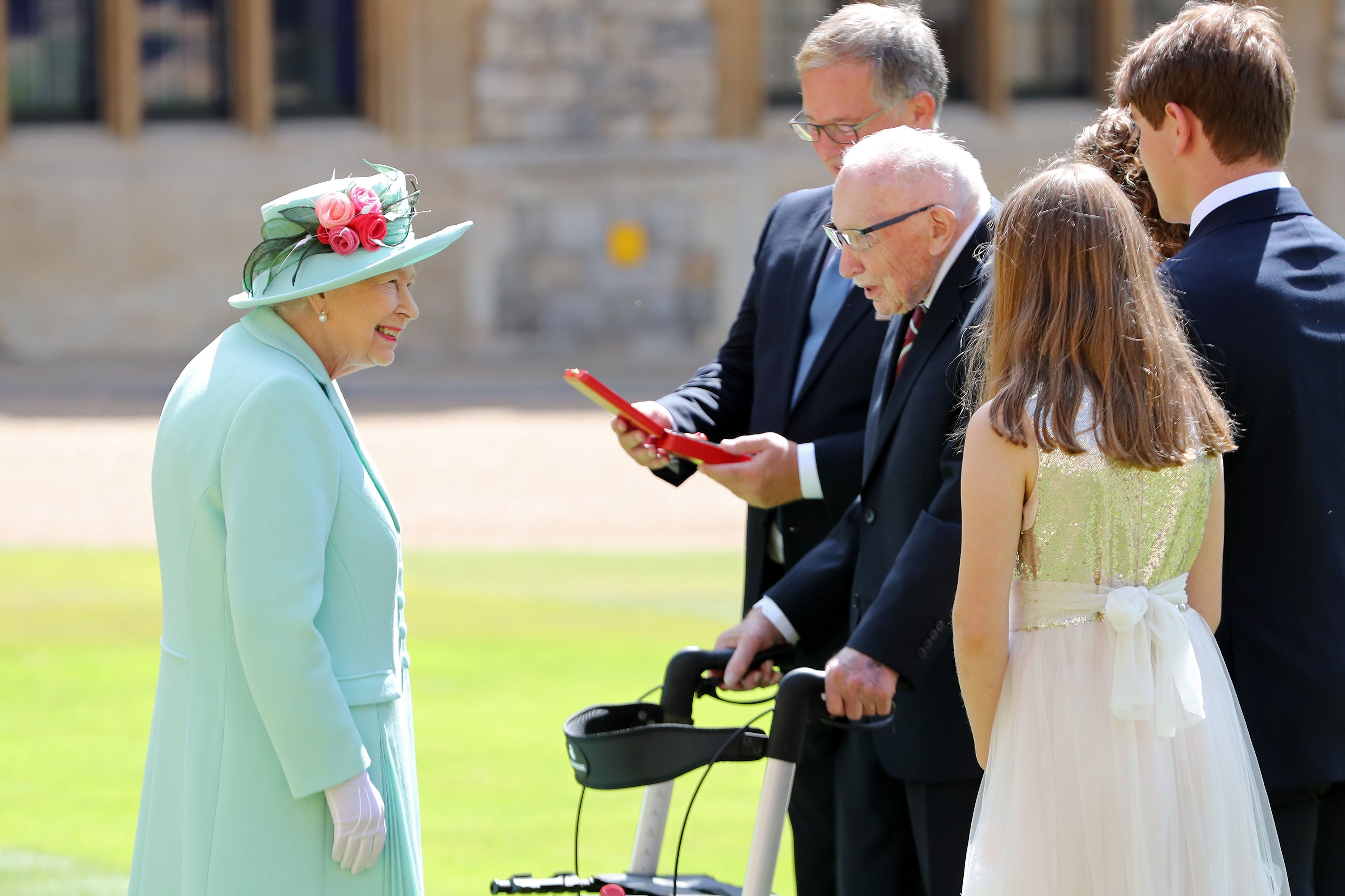 La Reina Isabel II conversa con el Capitán Thomas Moore y su familia después de nombrarlo como caballero durante una ceremonia en el Castillo de Windsor