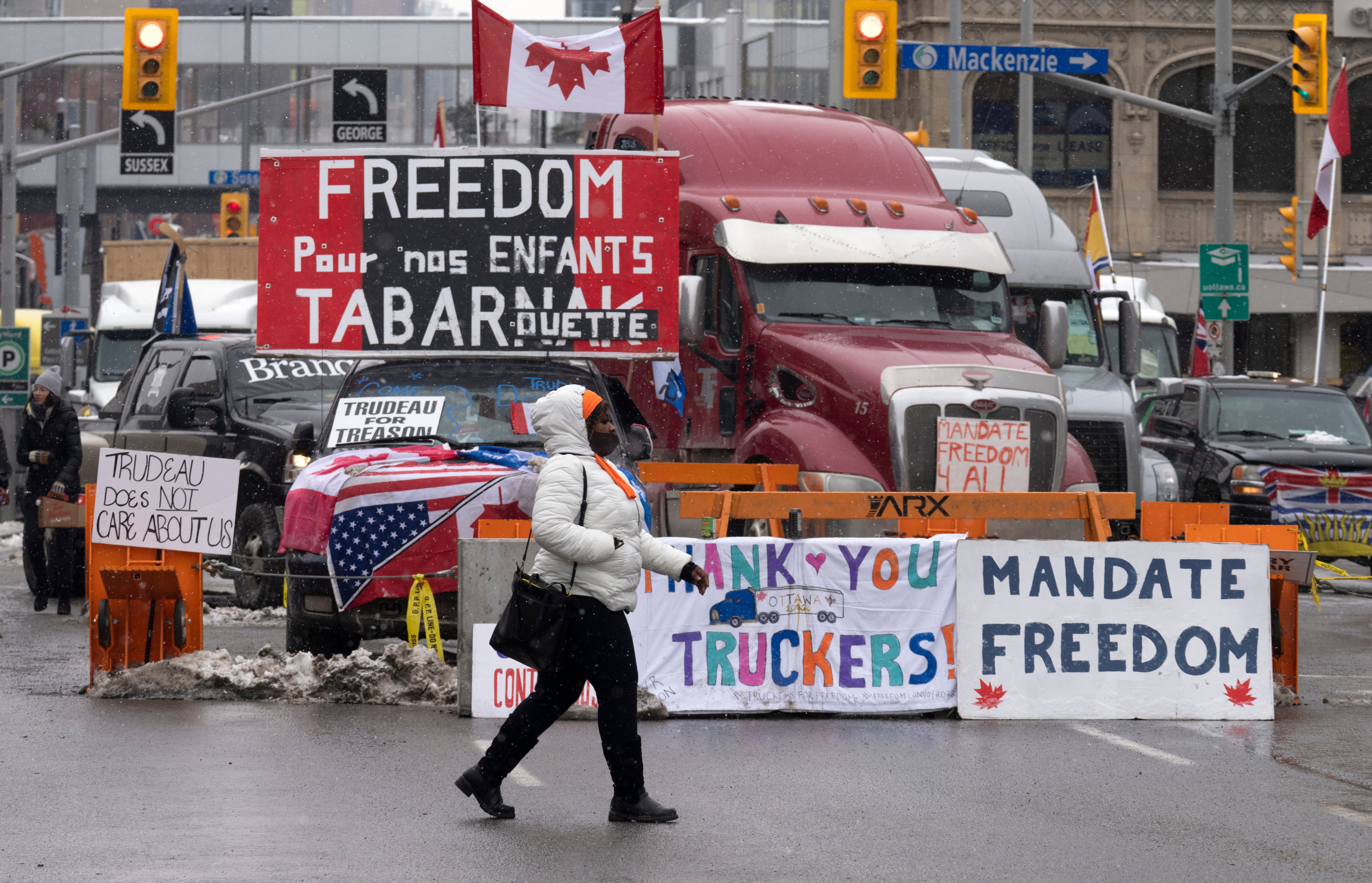 Una mujer cruza la calle frente a los vehículos estacionados como parte de la protesta de camioneros el martes 8 de febrero de 2022 en Ottawa