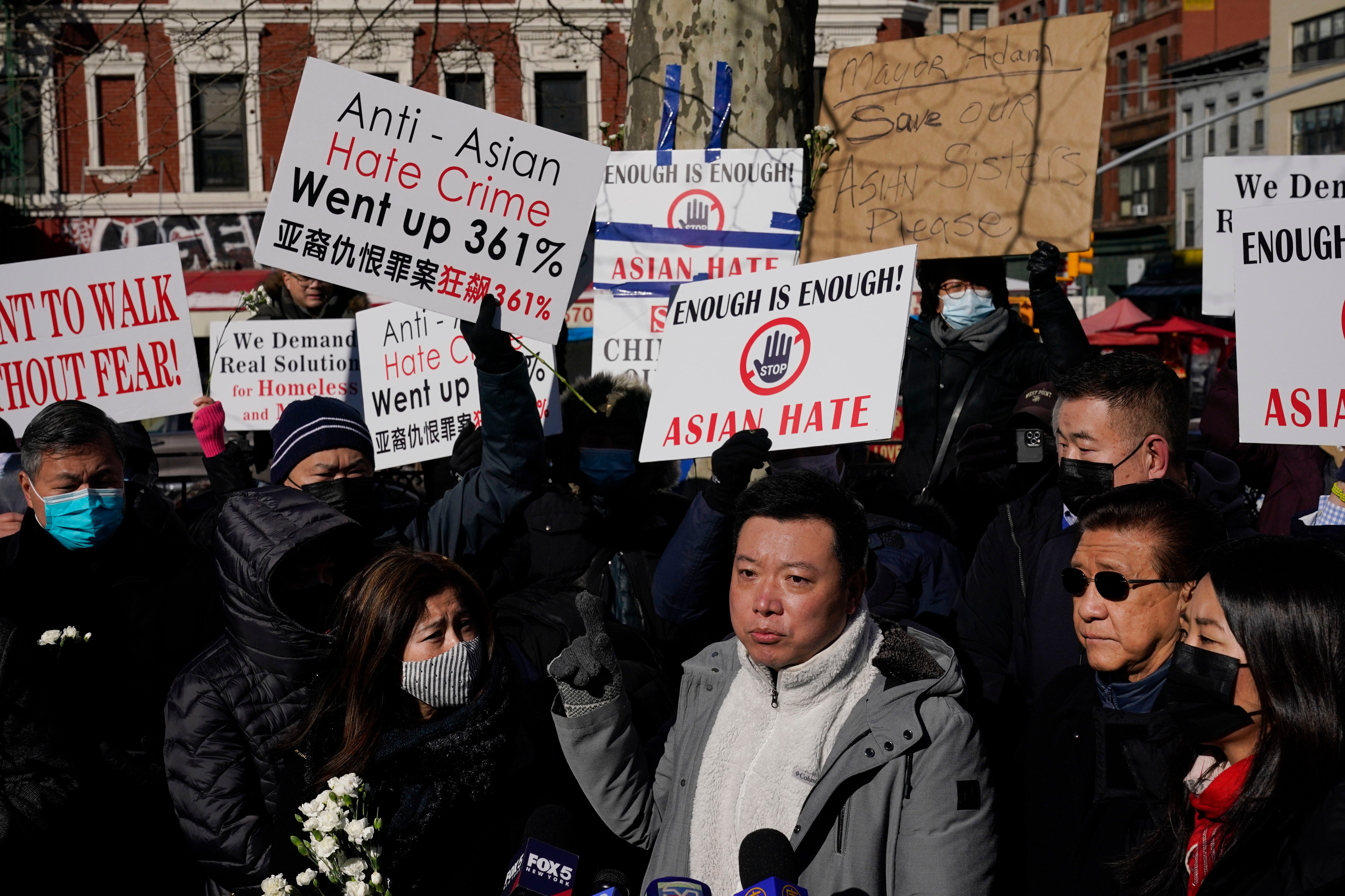 Los dolientes sostienen carteles exigiendo el fin de los ataques antiasiáticos en una vigilia por Lee