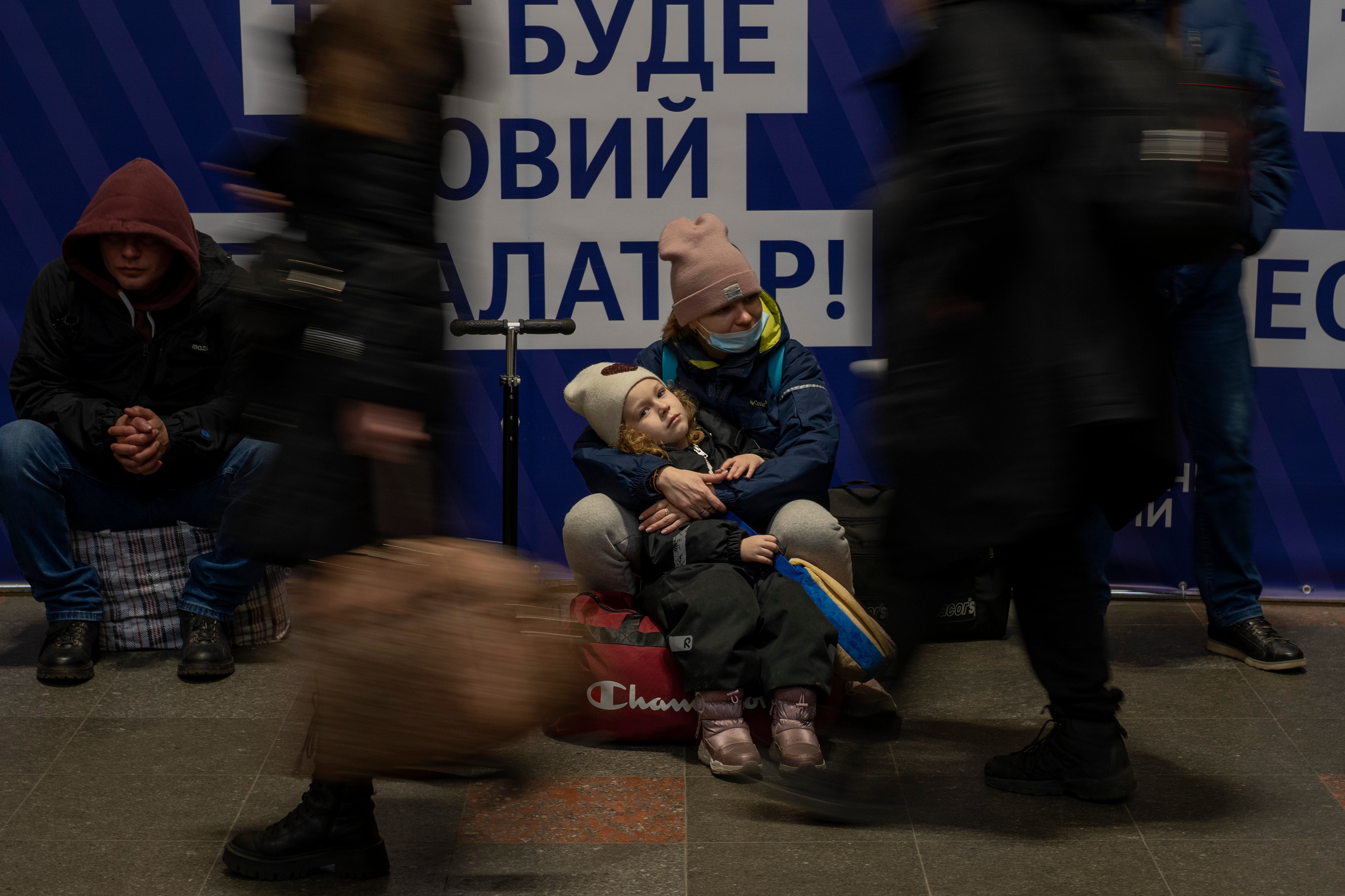 Una mujer con su hija espera un tren mientras intentan salir de Kiev