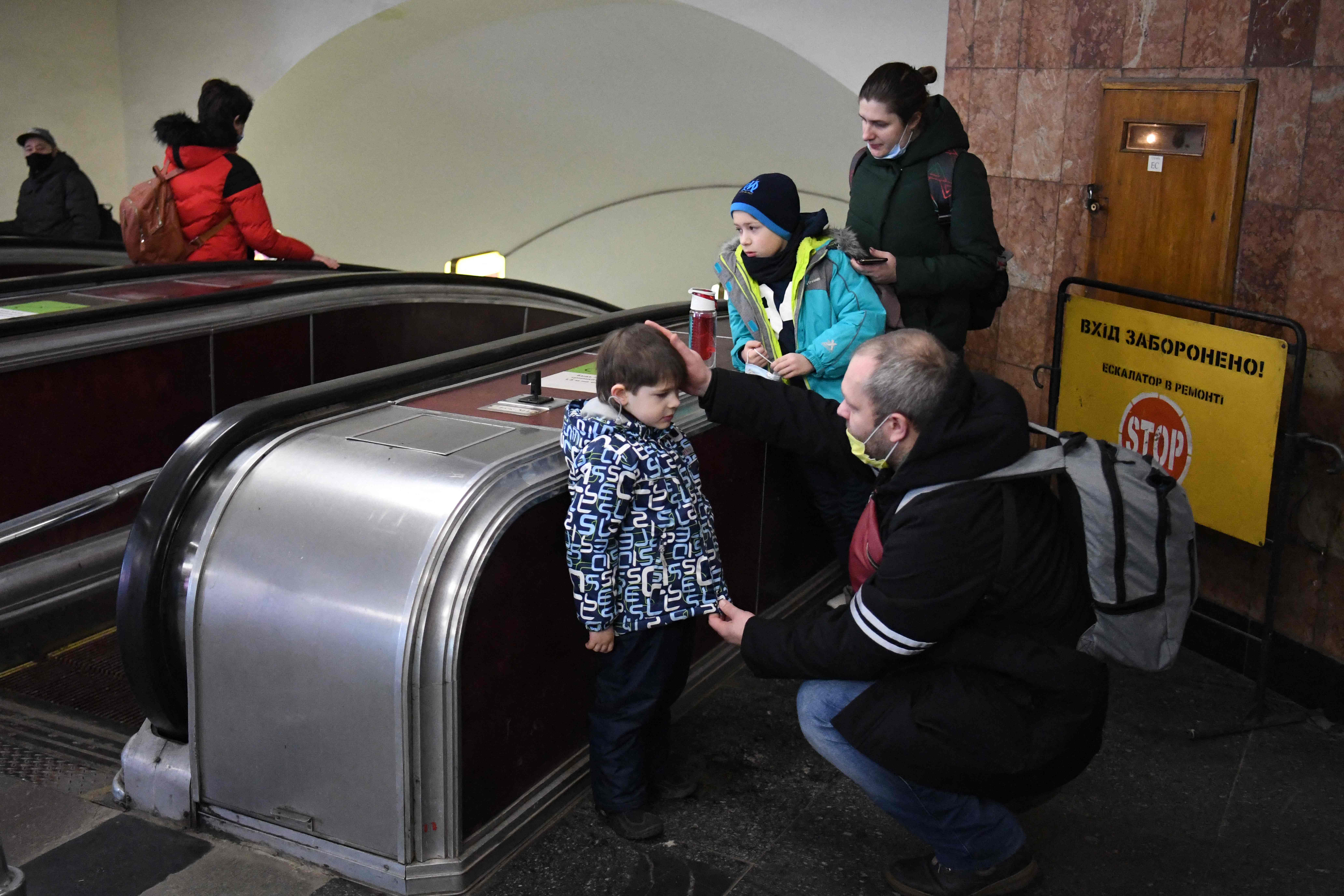 Un padre ucraniano tranquiliza a su hijo mientras la familia se refugia en una estación de metro de Kiev