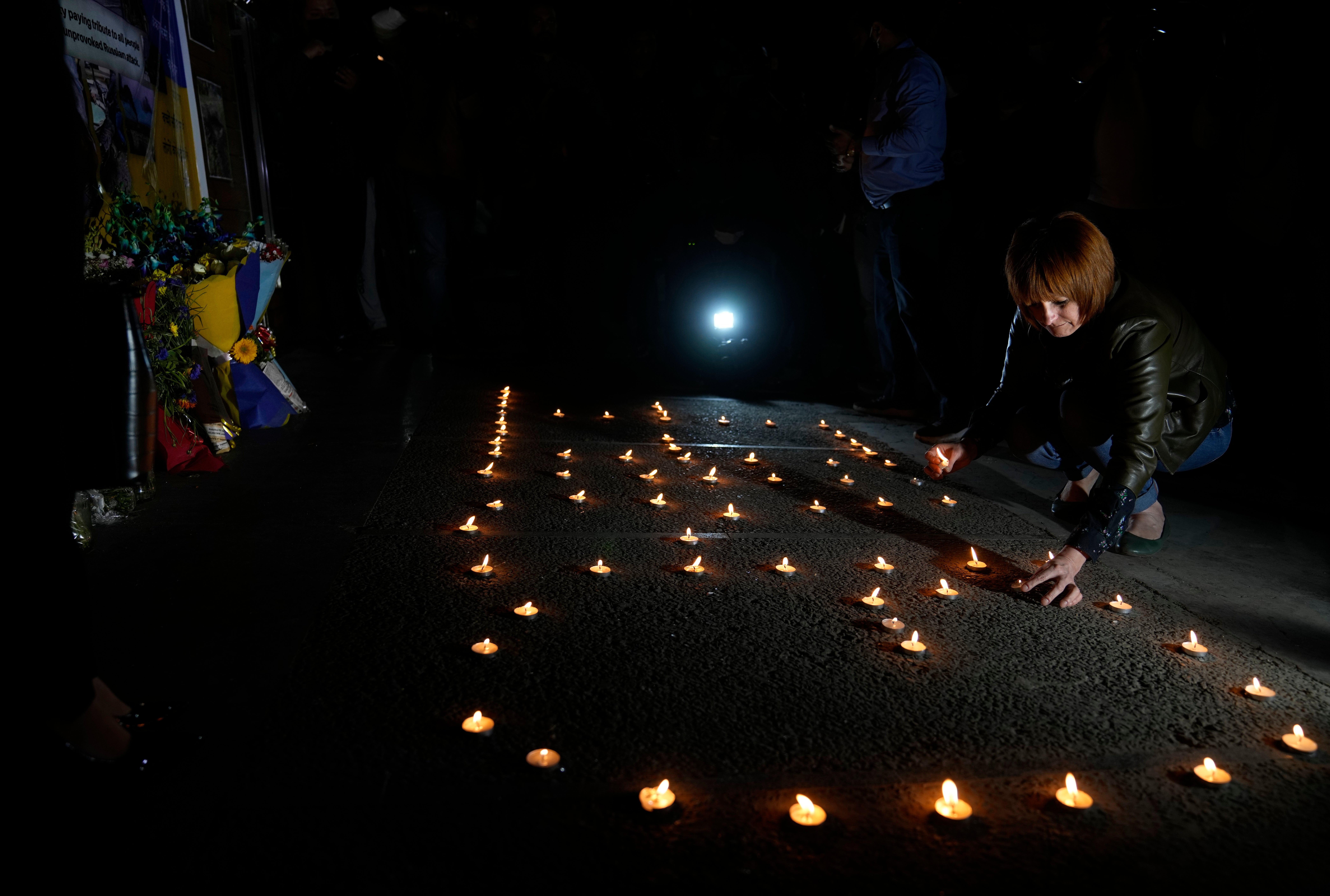 Una mujer ucraniana enciende una vela en conmemoración a las personas que han fallecido durante la invasión rusa