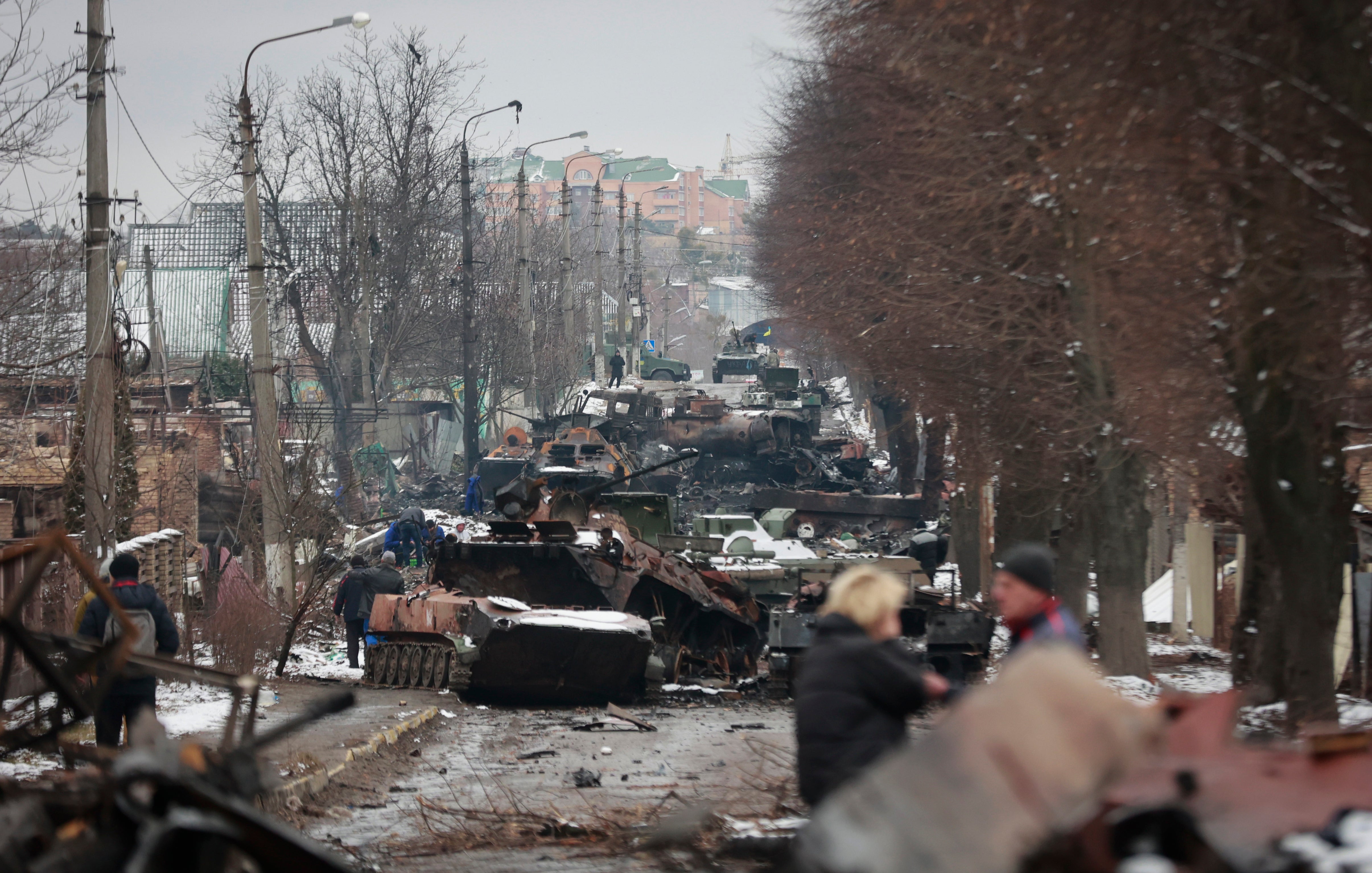 Las personas observan los restos de los vehículos militares rusos sobre un camino en el pueblo de Bucha, cerca de Kyiv, Ucrania, el martes 1 de marzo, 2022