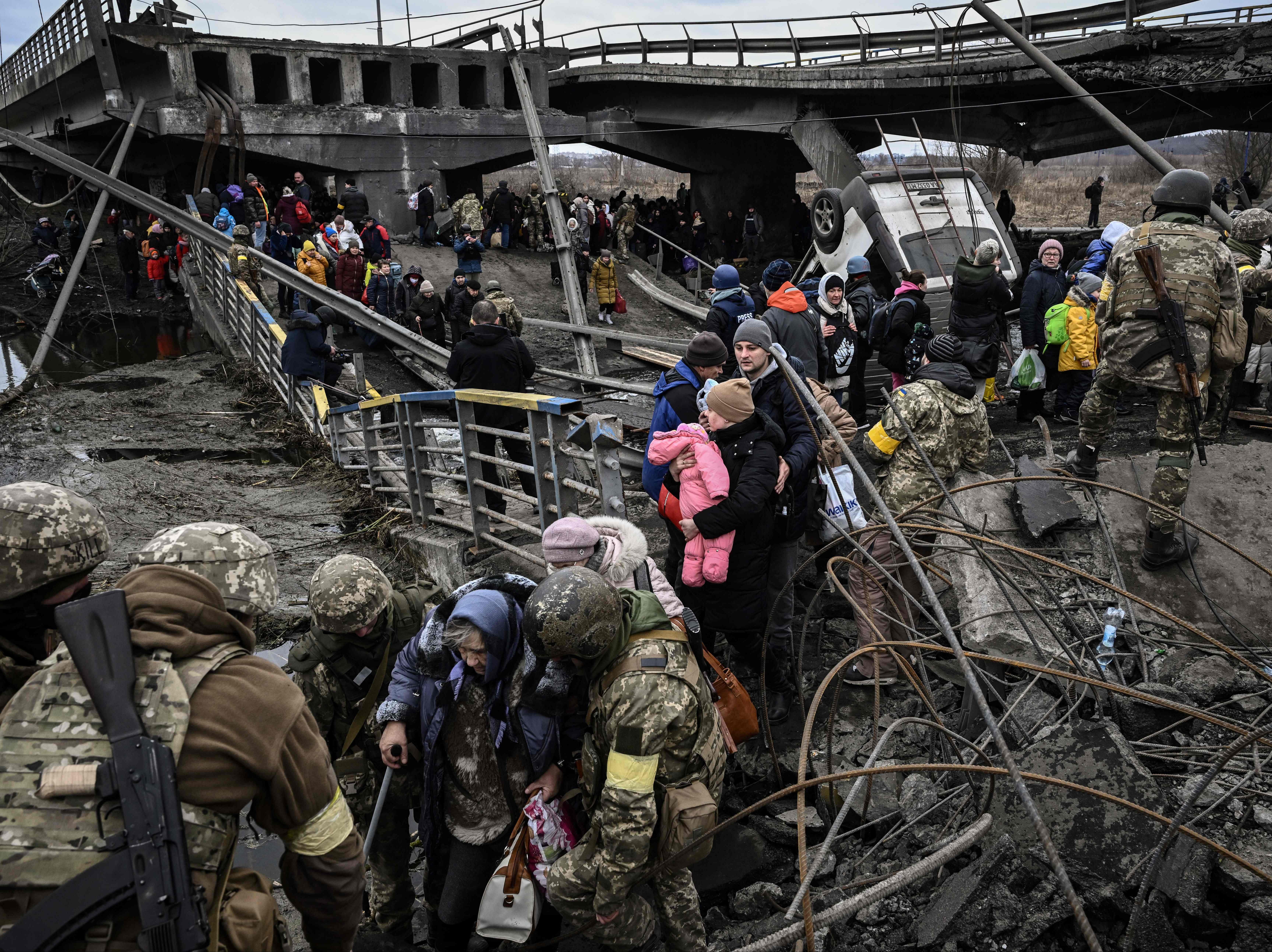 La gente cruza un puente destruido mientras evacua la ciudad de Irpin, al noroeste de Kyiv, durante un intenso bombardeo