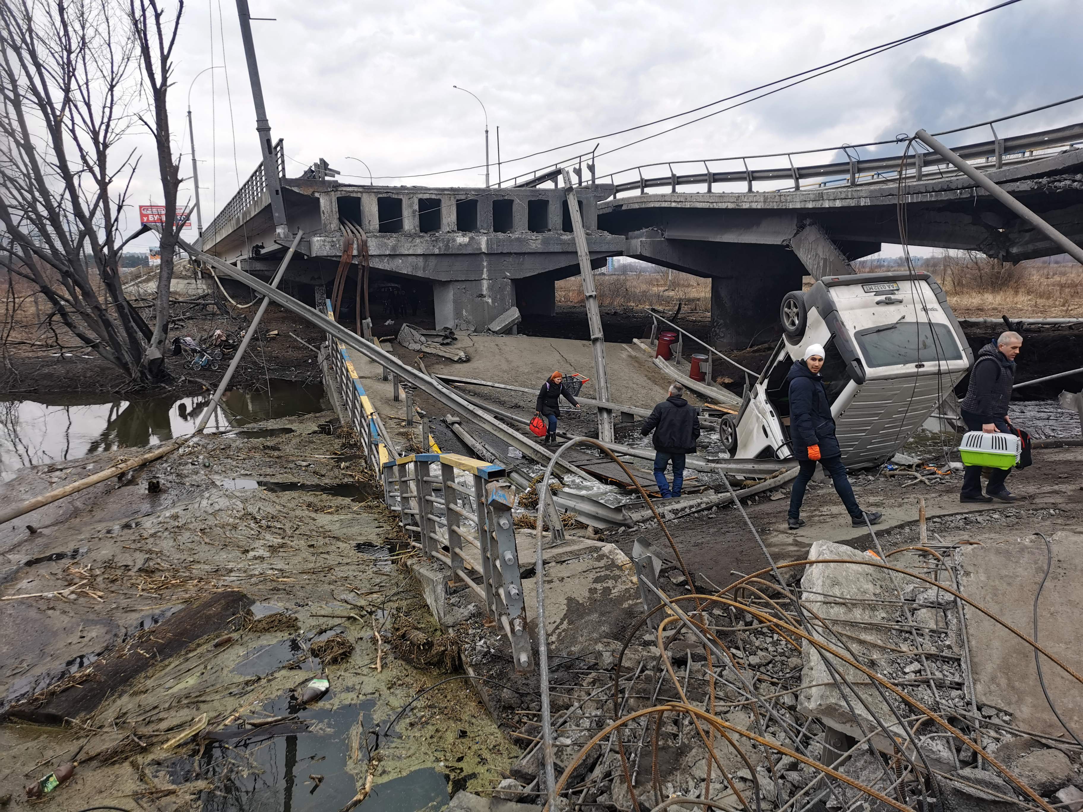 Unos peatones cruzan un puente destruido mientras evacuan la ciudad de Irpin, al noroeste de Kyiv, el 6 de marzo de 2022