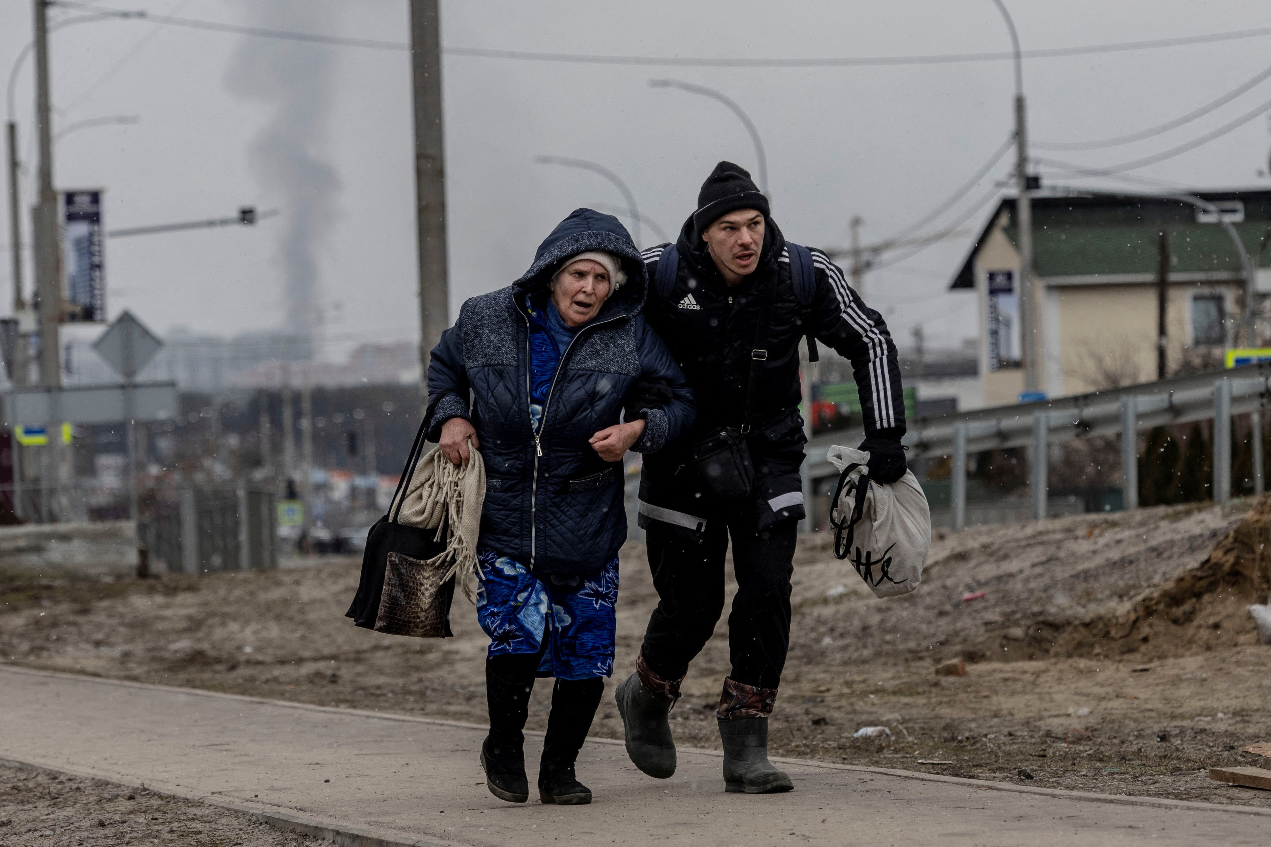 Un hombre ayuda a una anciana a refugiarse tras un intenso bombardeo en la única vía de escape utilizada por los lugareños, mientras las tropas rusas avanzan hacia la capital, en Irpin, cerca de Kyiv, 6 de marzo de 2022