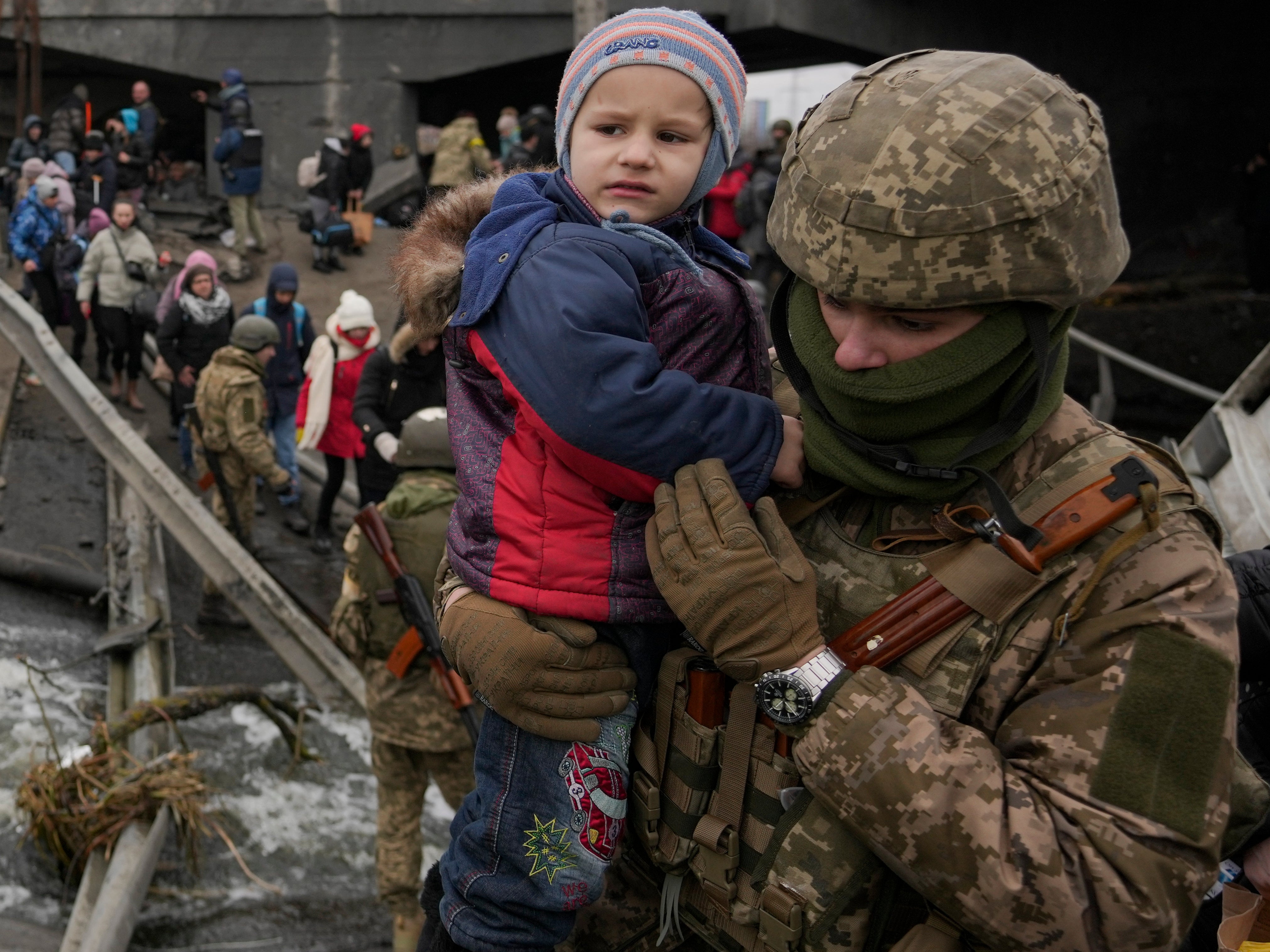 Un soldado ucraniano sostiene a un niño que cruza el río Irpin