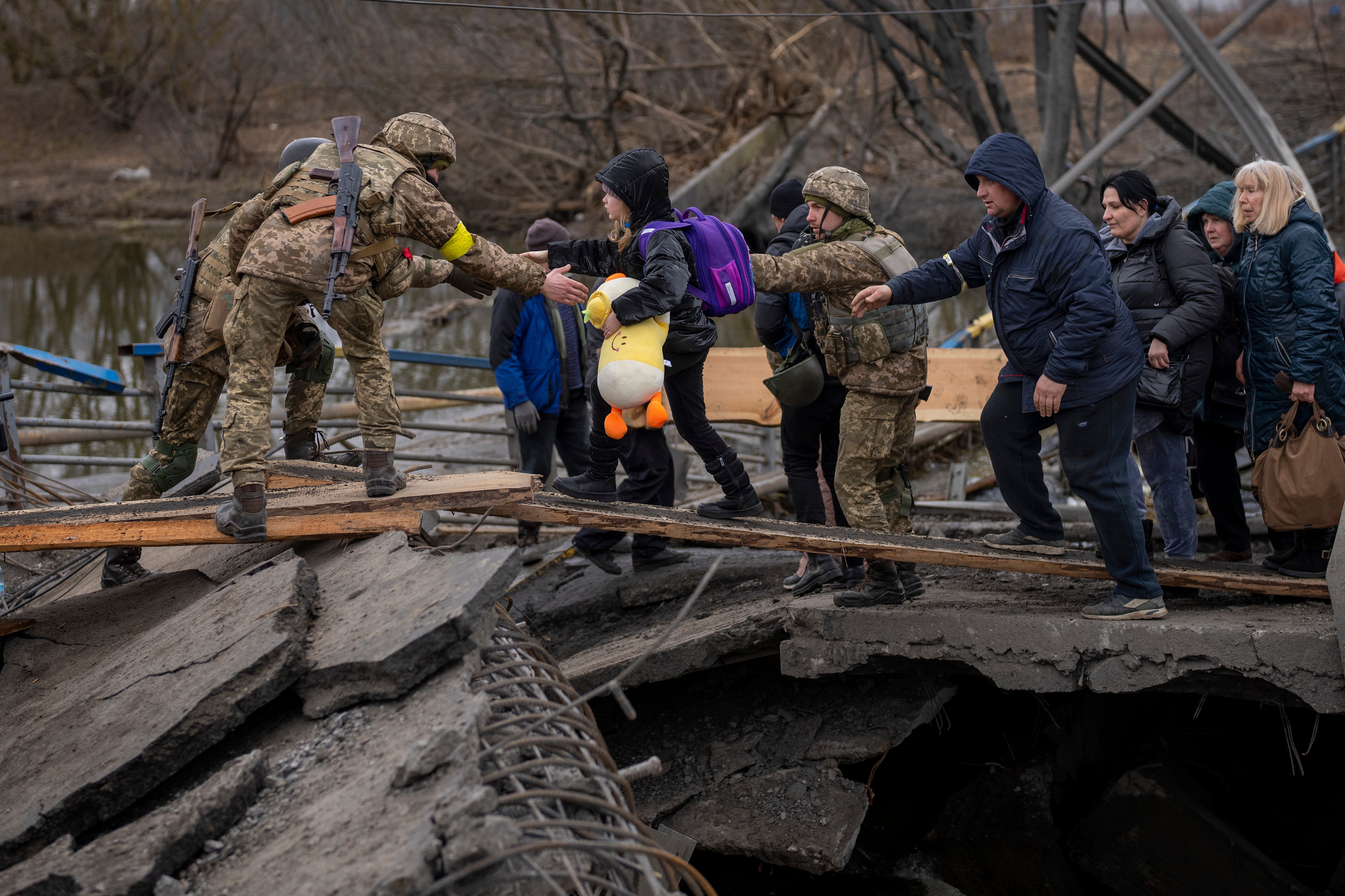 Soldados ucranianos ayudan a una familia que huye a cruzar el río Irpin en las afueras de Kyiv