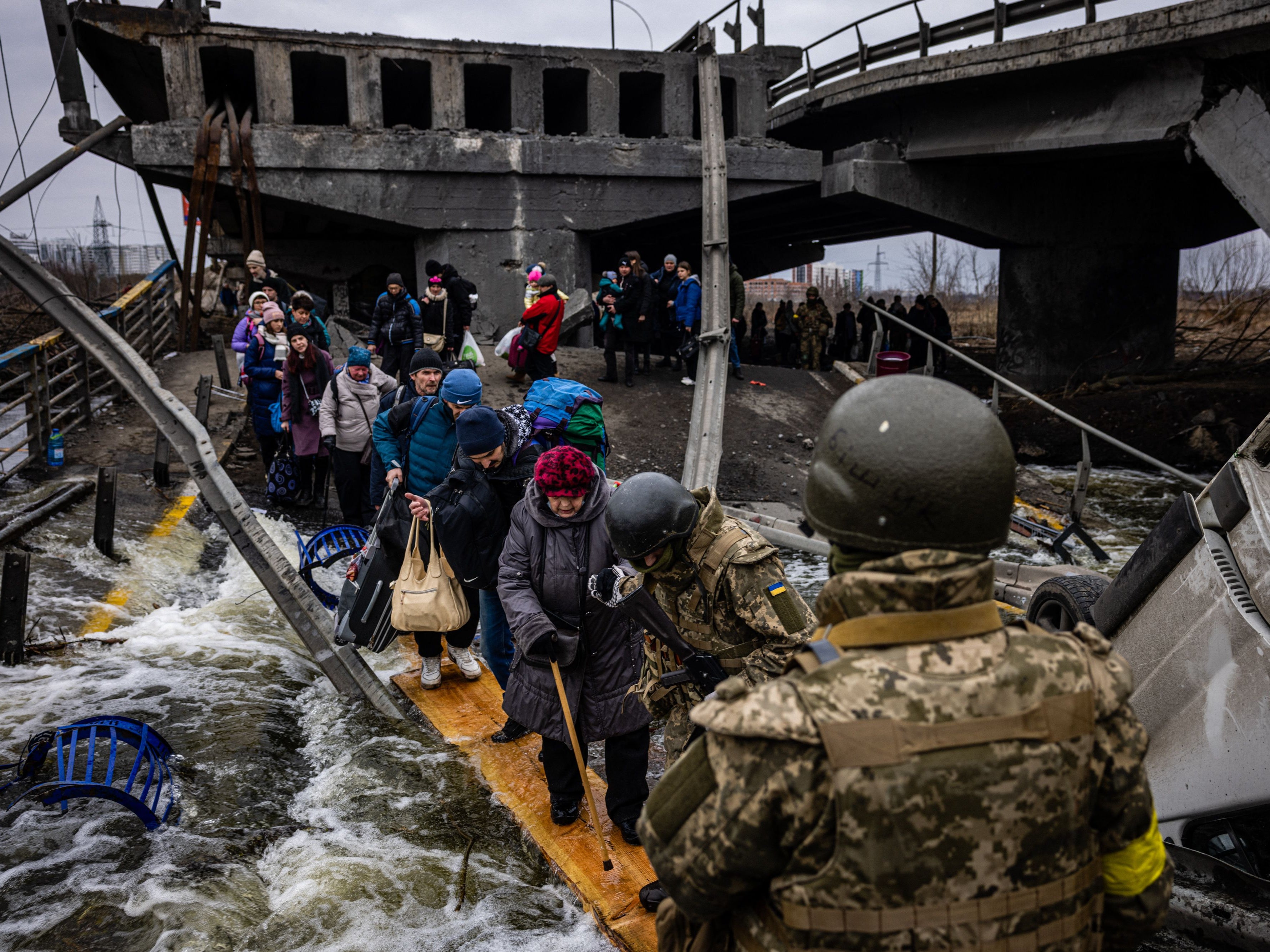 Los refugiados cruzan un puente destruido para huir de la ciudad de Irpin, al noroeste de Kyiv, el 7 de marzo de 2022