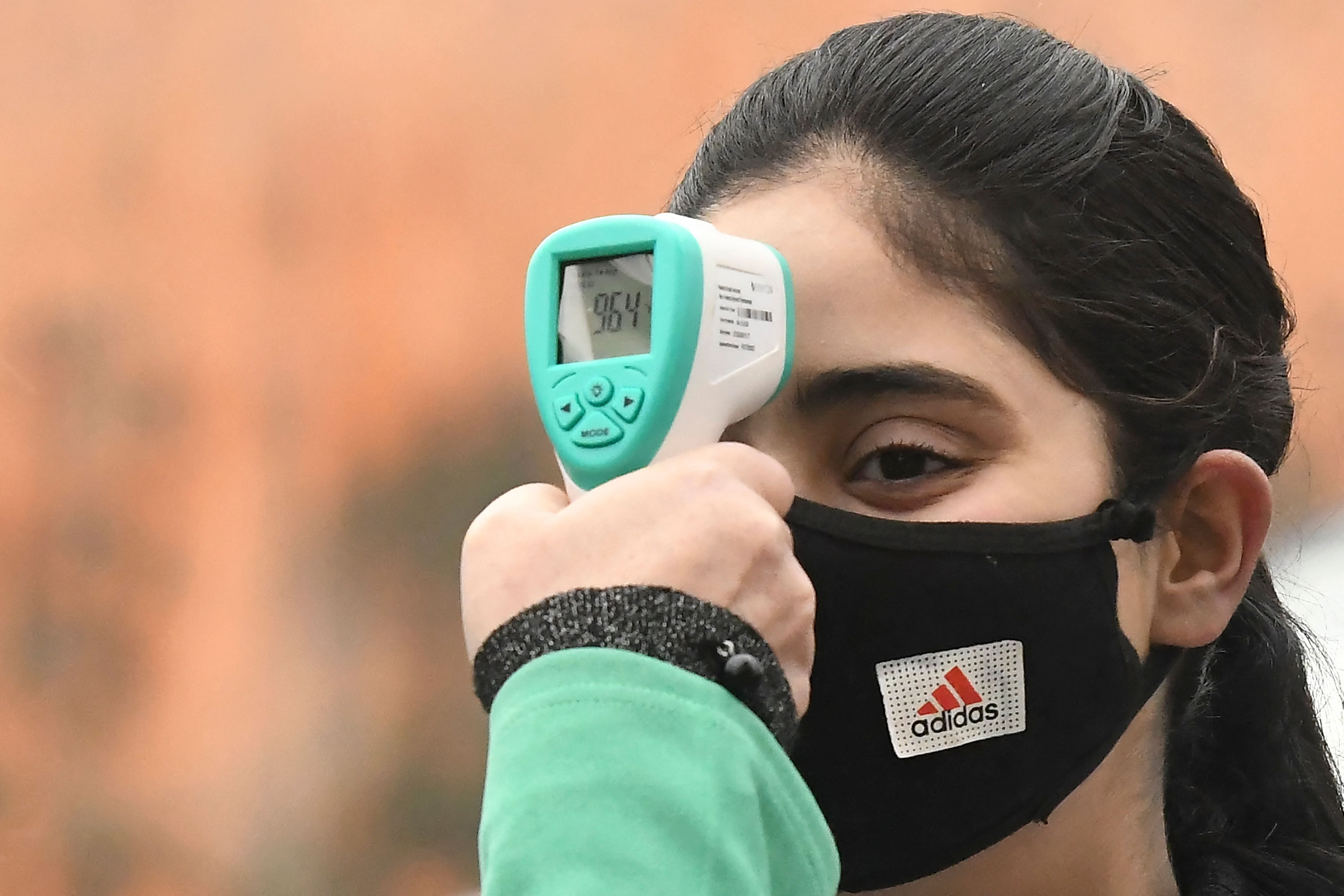 Una enfermera revisa la temperatura del estudiantado en Kashmir, India