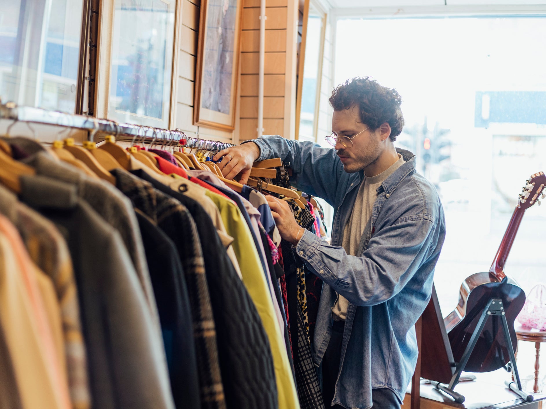 Un hombre busca ropa de segunda mano en una tienda benéfica en Newcastle-upon-Tyne. Según académicos, las personas deberían limitarse a comprar tres prendas nuevas al año.
