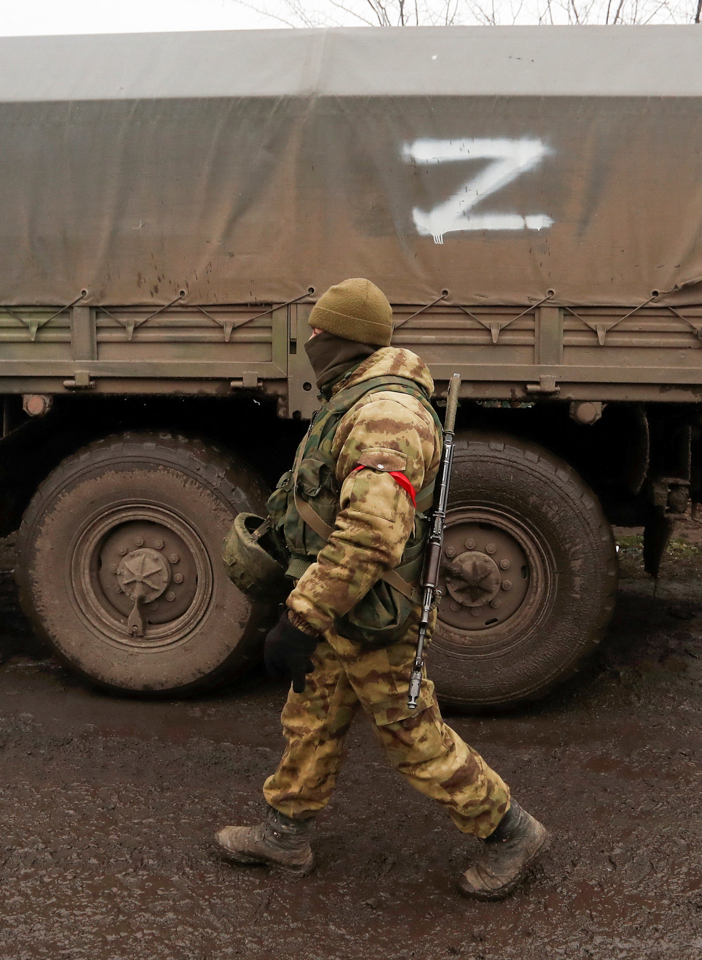 Un miembro de las tropas prorrusas con un uniforme sin insignias pasa junto a un camión con el símbolo “Z” pintado en su lateral en el asentamiento de Rybinskoye, controlado por los separatistas, durante el conflicto entre Ucrania y Rusia en la región de Donetsk, Ucrania, el 5 de marzo