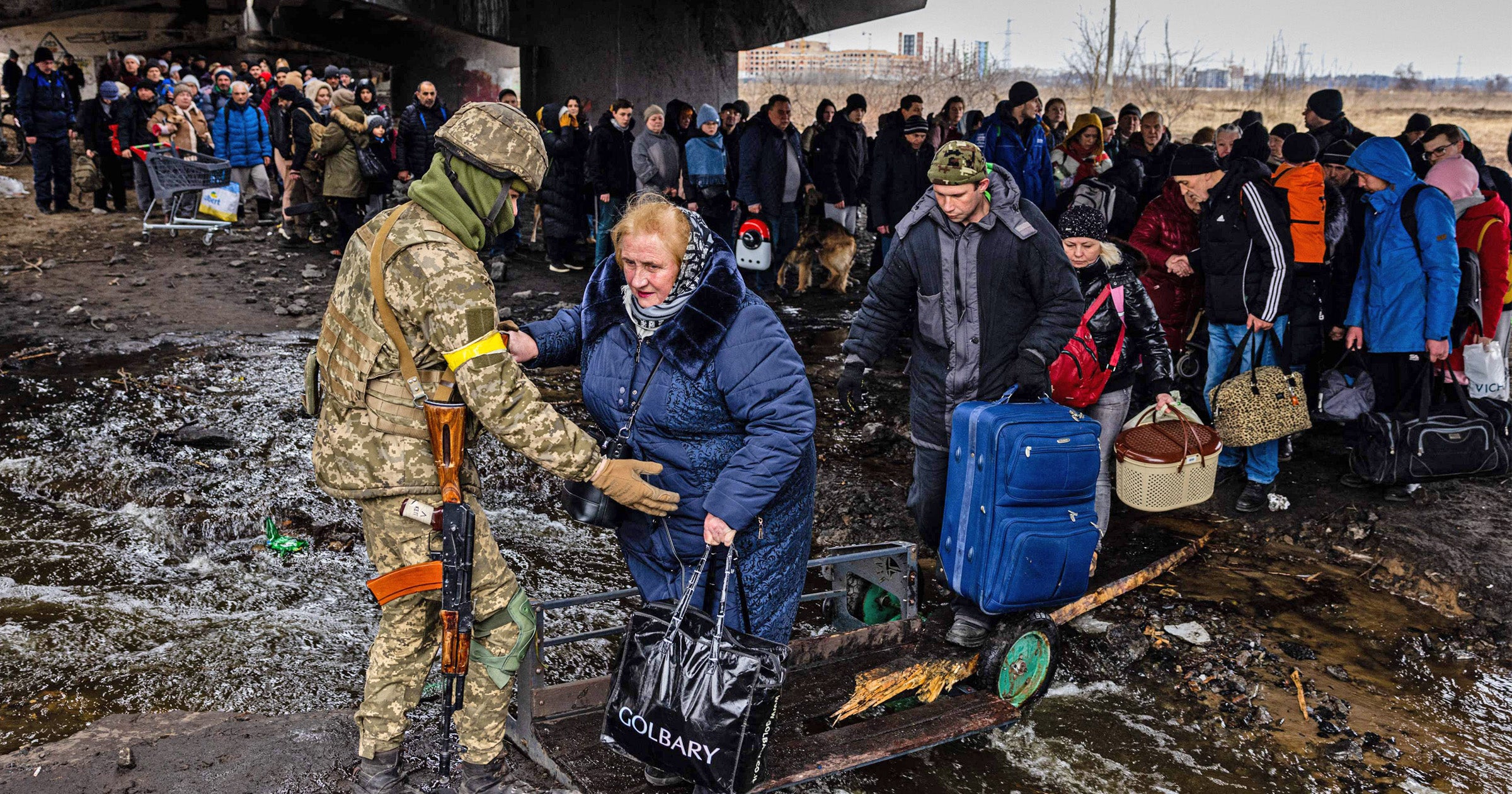 Un soldado ucraniano ayuda a las personasque huyen de Irpin, al noroeste de Kyiv