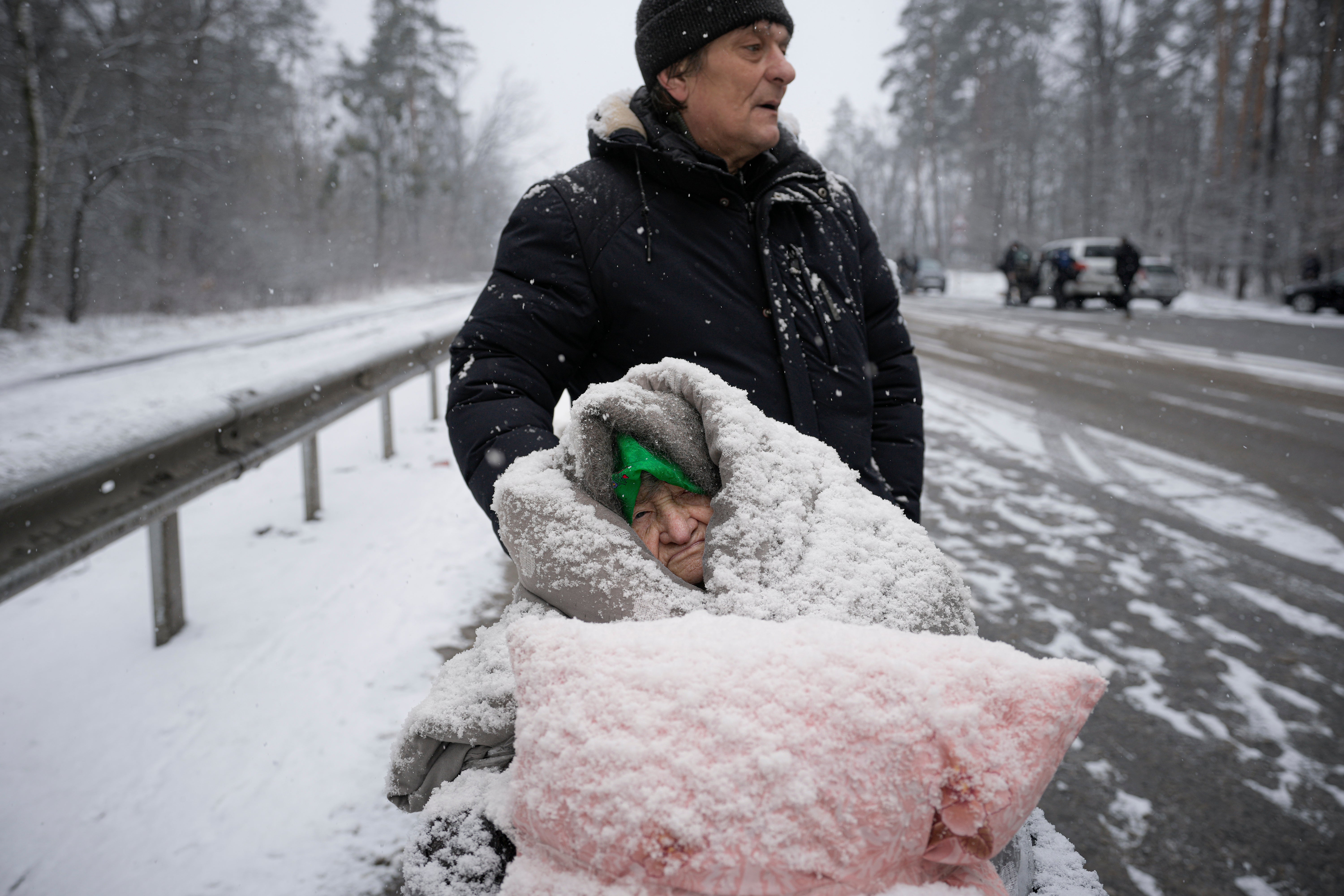 Una mujer anciana está cubierta de nieve mientras está sentada en una silla de ruedas después de haber sido evacuada de Irpin, en las afueras de Kyiv, Ucrania