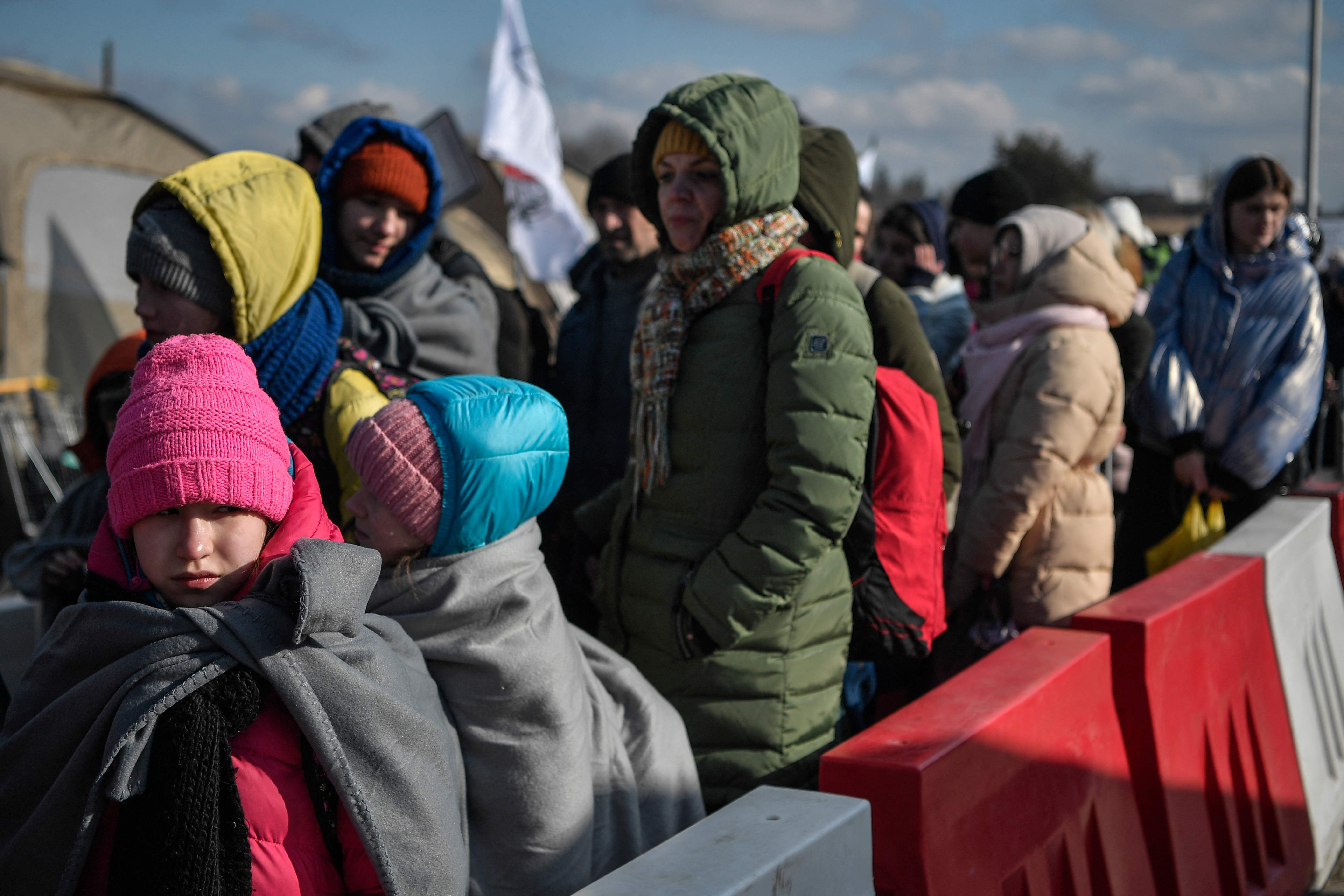 Personas esperan para subir a los autobuses tras cruzar la frontera ucraniana con Polonia, 10 de marzo de 2022