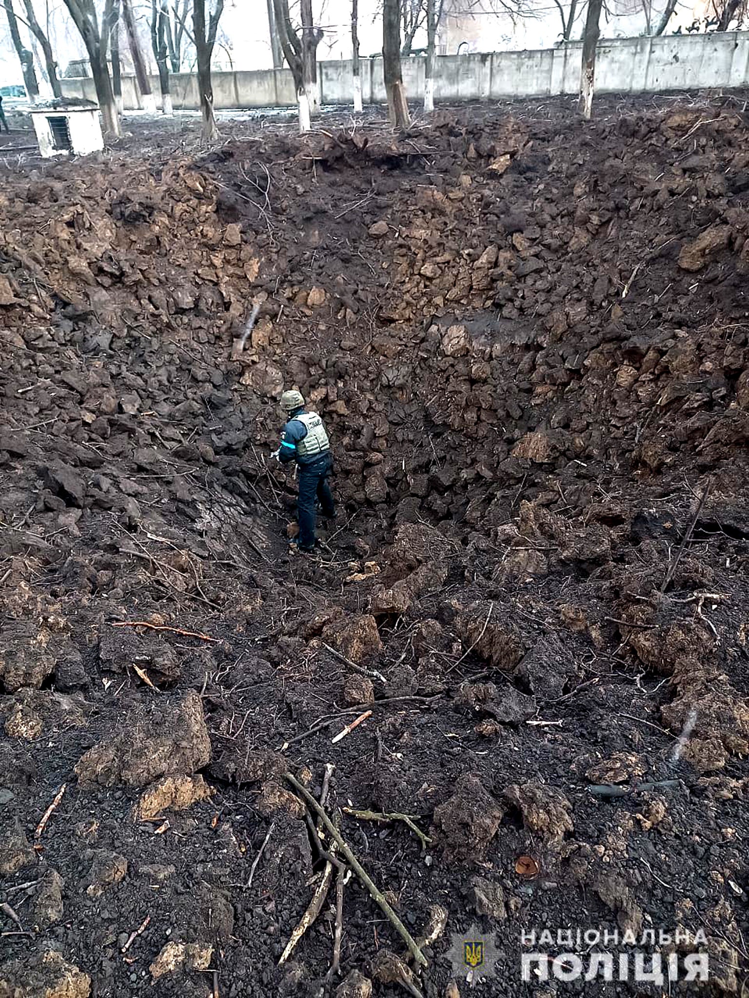 Un agente de policía inspecciona un cráter en el terreno del hospital de maternidad en Mariupol bombardeado el miércoles