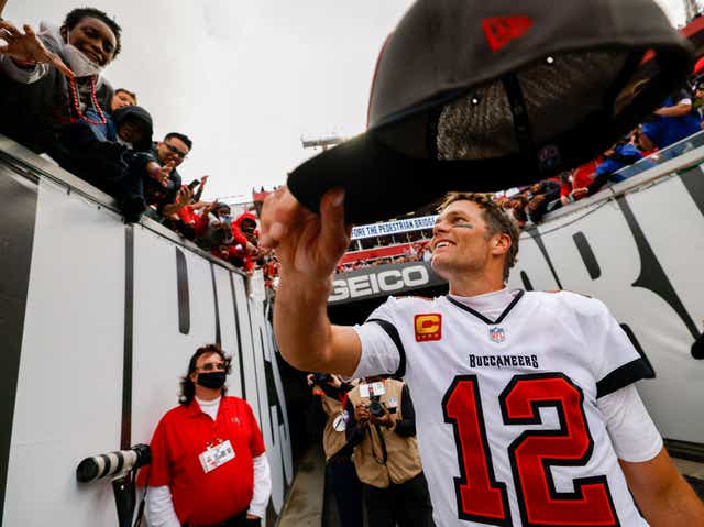 <p>Tom Brady hands fans his hat after beating the Philadelphia Eagles in January 2022</p>