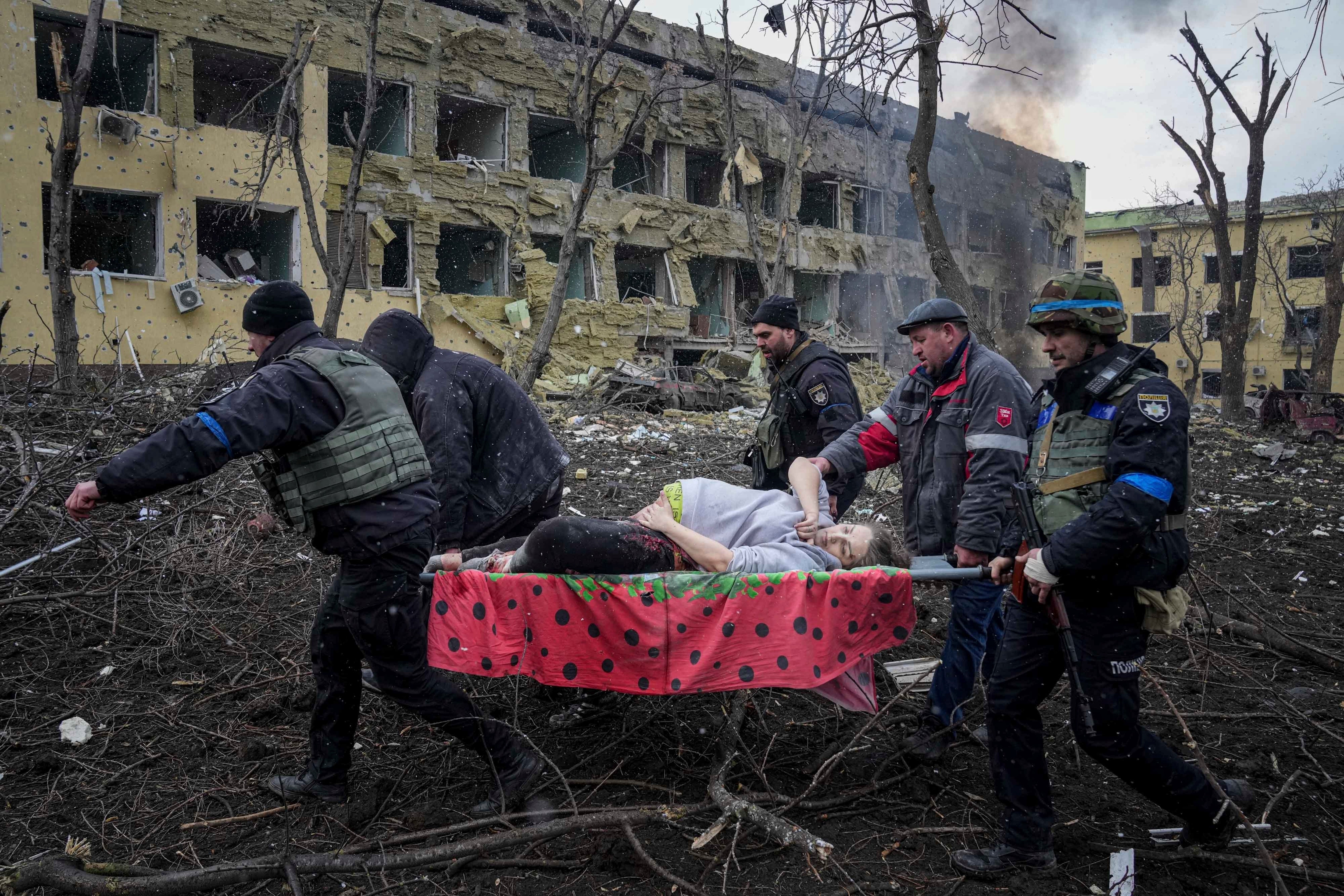 Empleados y voluntarios de emergencias ucranianos sacan a una mujer embarazada herida de la clínica de maternidad dañada por los bombardeos en Mariúpol
