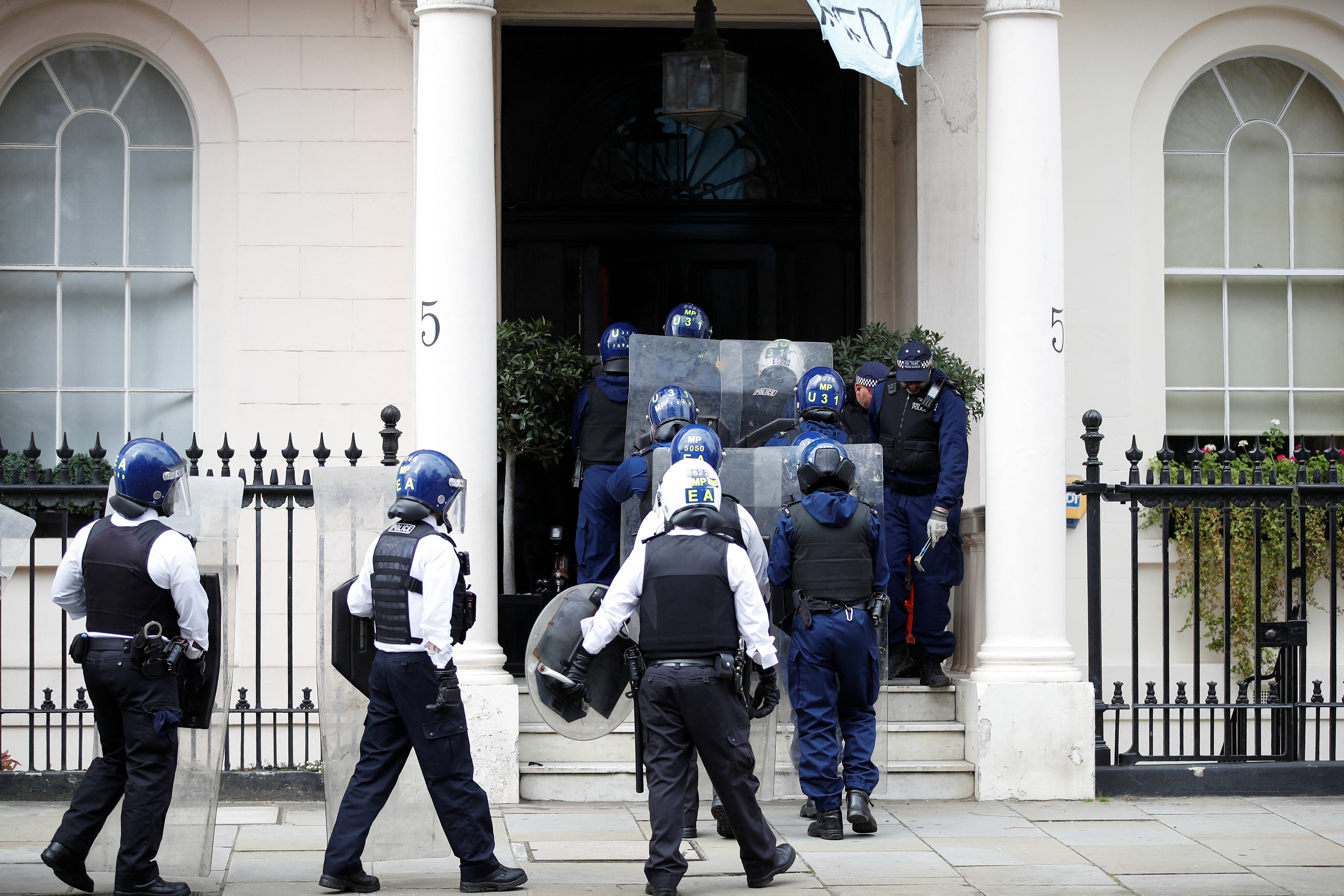 Police officers enter the mansion belonging to Russian billionaire Oleg Deripaska