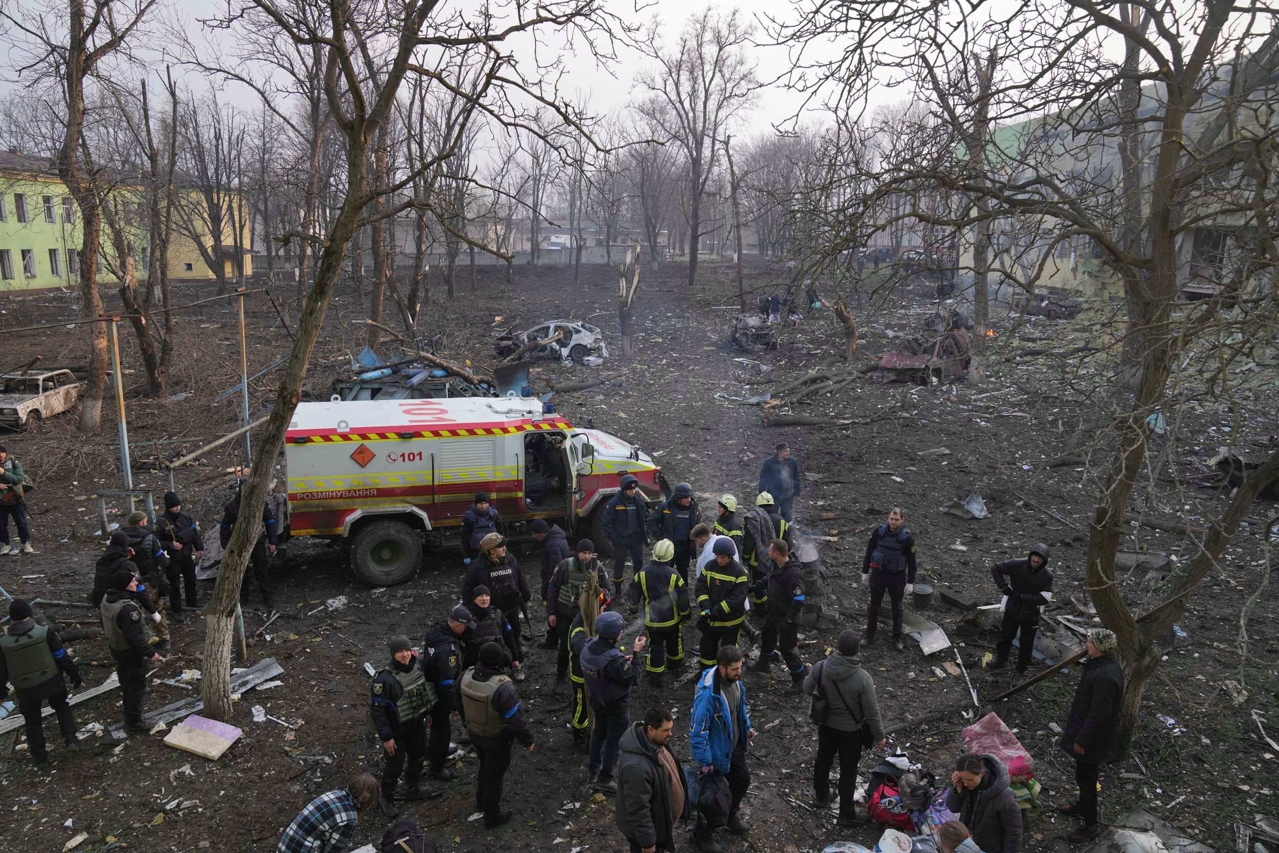 Militares y bomberos ucranianos en el exterior de una clínica de maternidad dañada por un bombardeo en Mariúpol