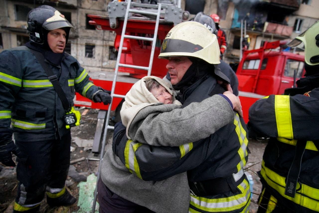 Rescatistas ayudan a una mujer a evacuar un edificio residencial que fue atacado, mientras continúa el ataque de Rusia a Ucrania, en Kyiv