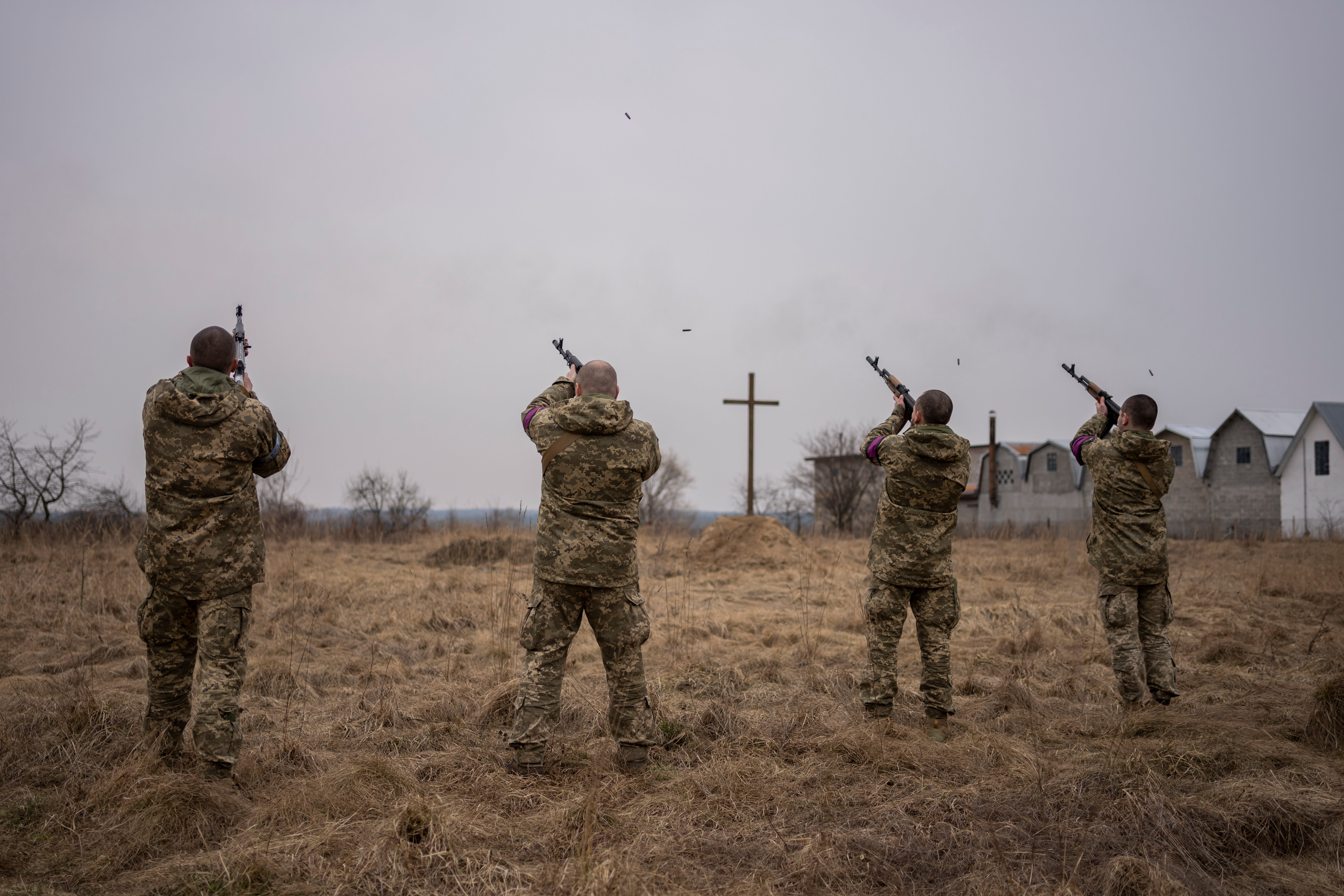 Soldados ucranianos en servicio disparan en señal de saludo durante el funeral de sus compañeros Roman Rak y Mykola Mykytiuk, en Starychi, al oeste de Ucrania, el miércoles 16 de marzo de 2022
