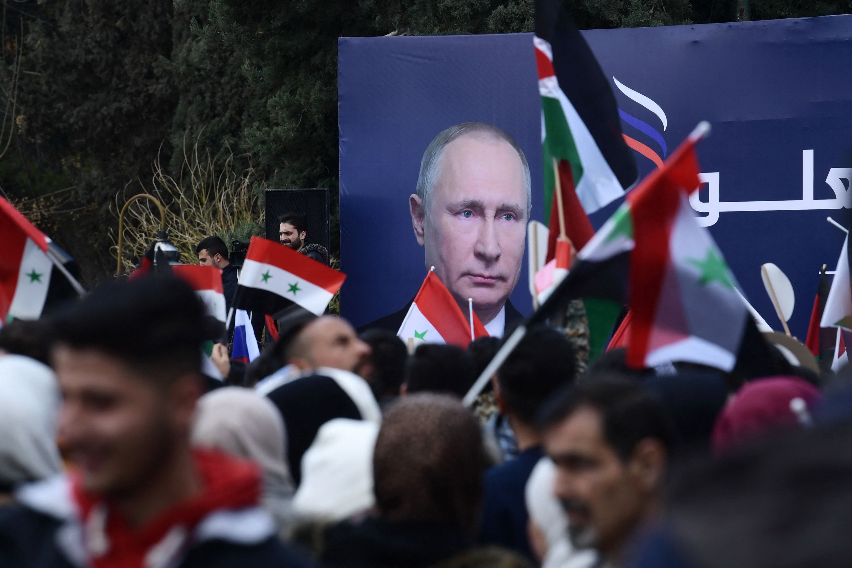 Estudiantes sirios ondean banderas sirias, rusas y palestinas en una manifestación a favor de Rusia