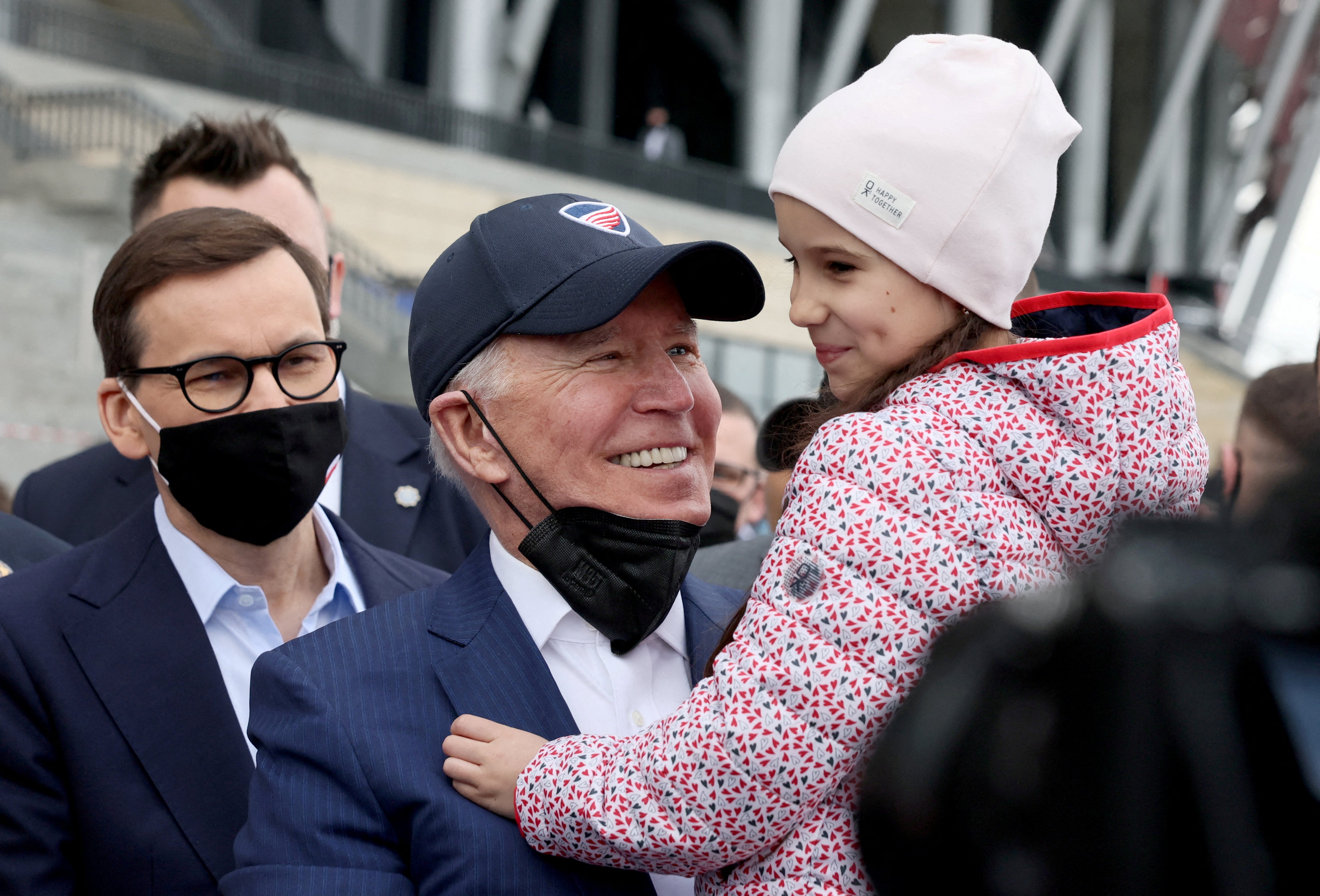 El presidente de EE.UU. Joe Biden, flanqueado por el primer ministro polaco Mateusz Morawiecki, sostiene a un niño mientras visita a los refugiados ucranianos en el Estadio Nacional PGE de Varsovia, Polonia