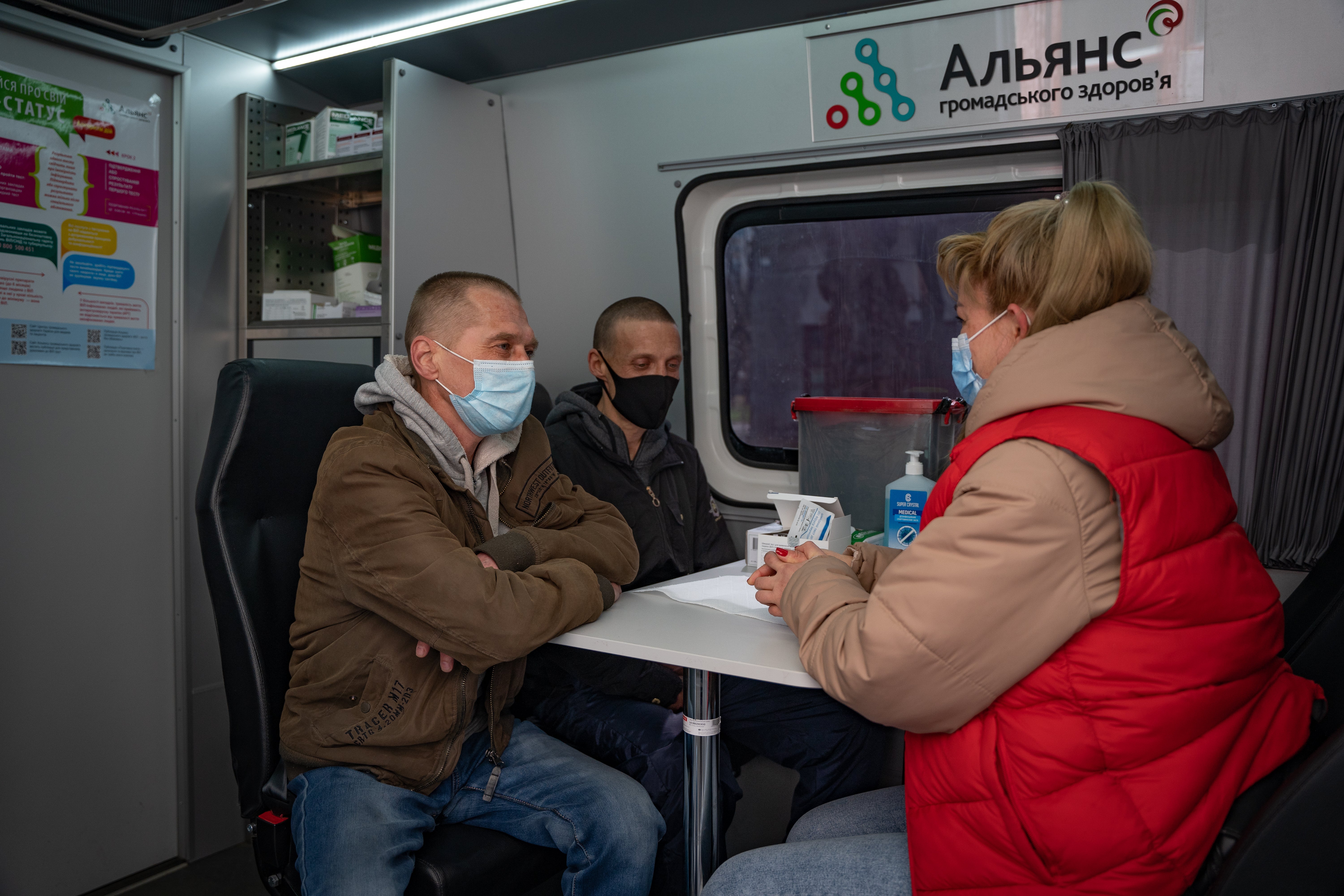 Liudmyla, una trabajadora social, se sienta en una clínica móvil de la APH en Odesa con dos de sus clientes; ambos necesitan tratamiento para el VIH