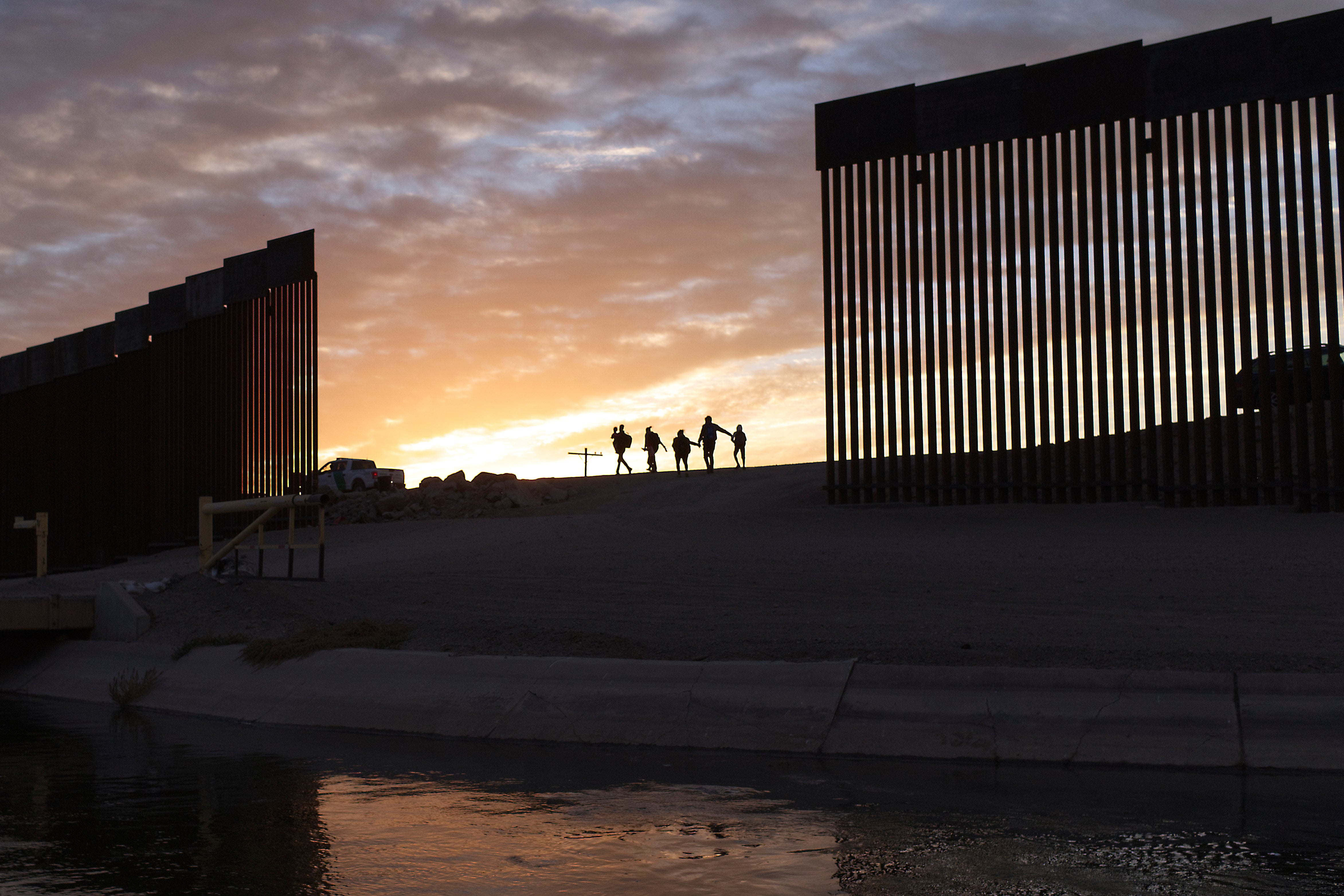 Migrantes pasan por un espacio en el muro de la frontera cerca de Yuma y Arizona (archivo)