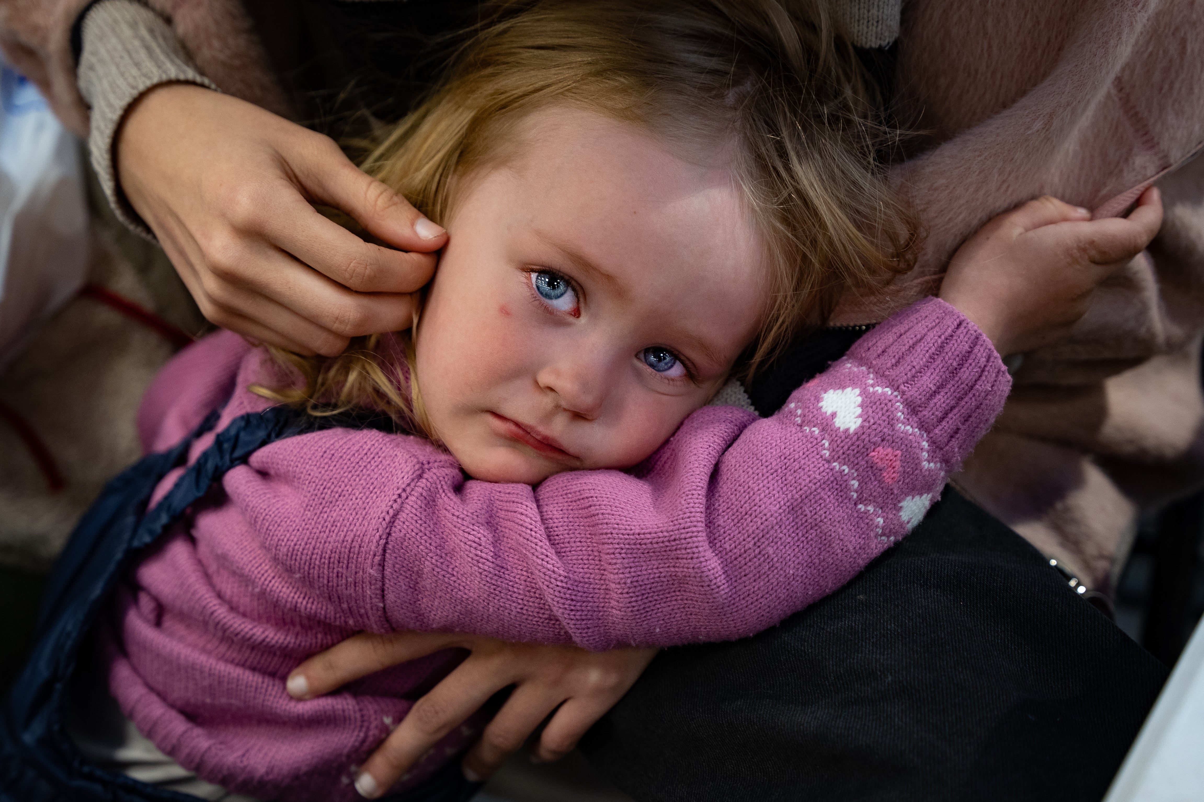 Paulina, quien tiene solo 2 años, es consolada por su hermana después de huir de Mariúpol