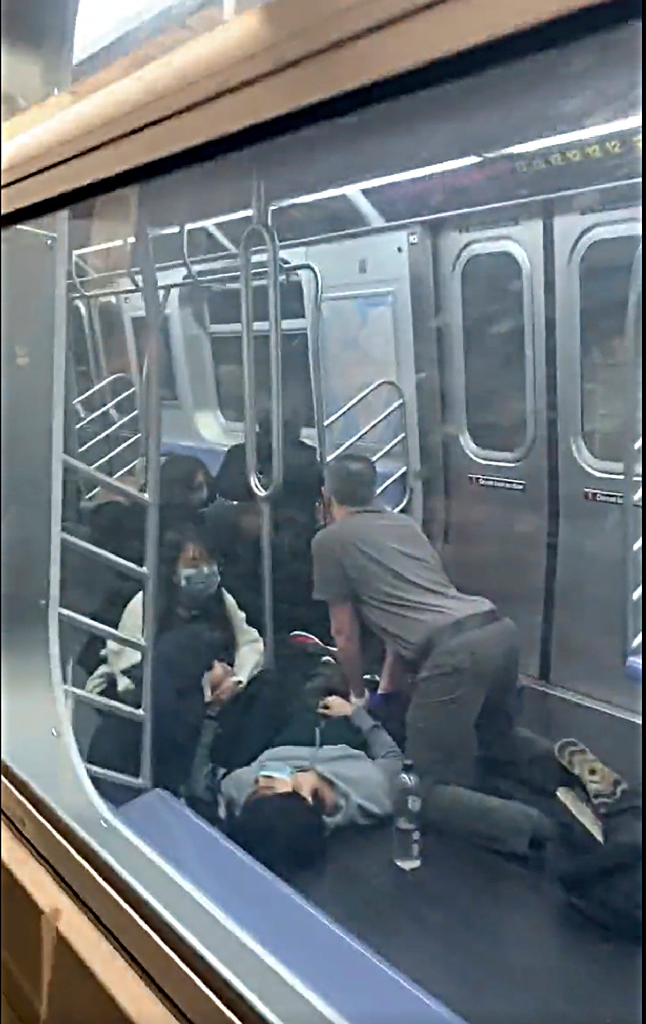 En esta foto facilitada por Will B Wylde, una persona es auxiliada en un auto del metro en el barrio neoyorquino de Brooklyn el 12 de abril