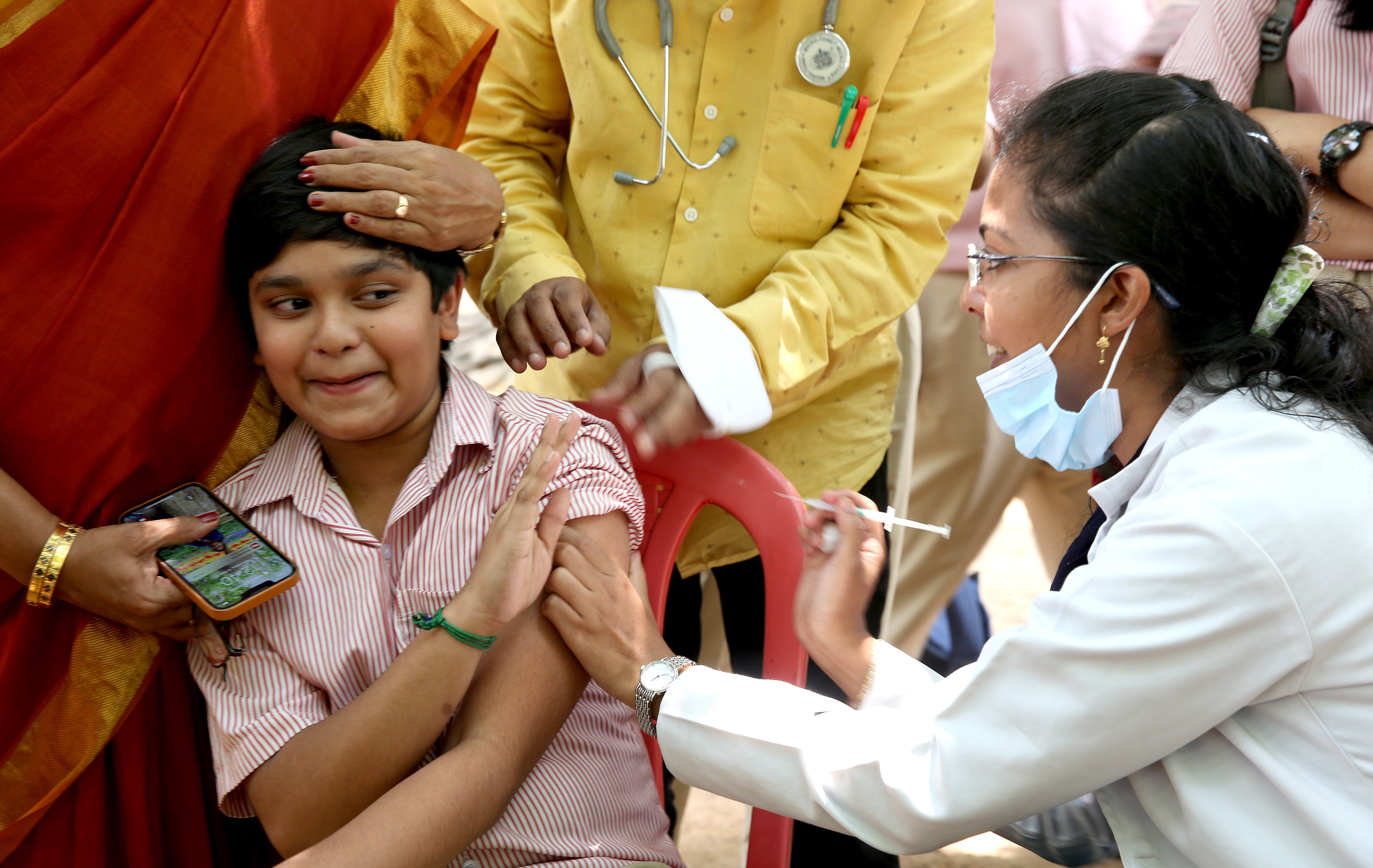 Un estudiante reacciona al recibir la vacuna contra el covid-19 durante una campaña de vacunación para niños de 12 a 14 años en Bangalore