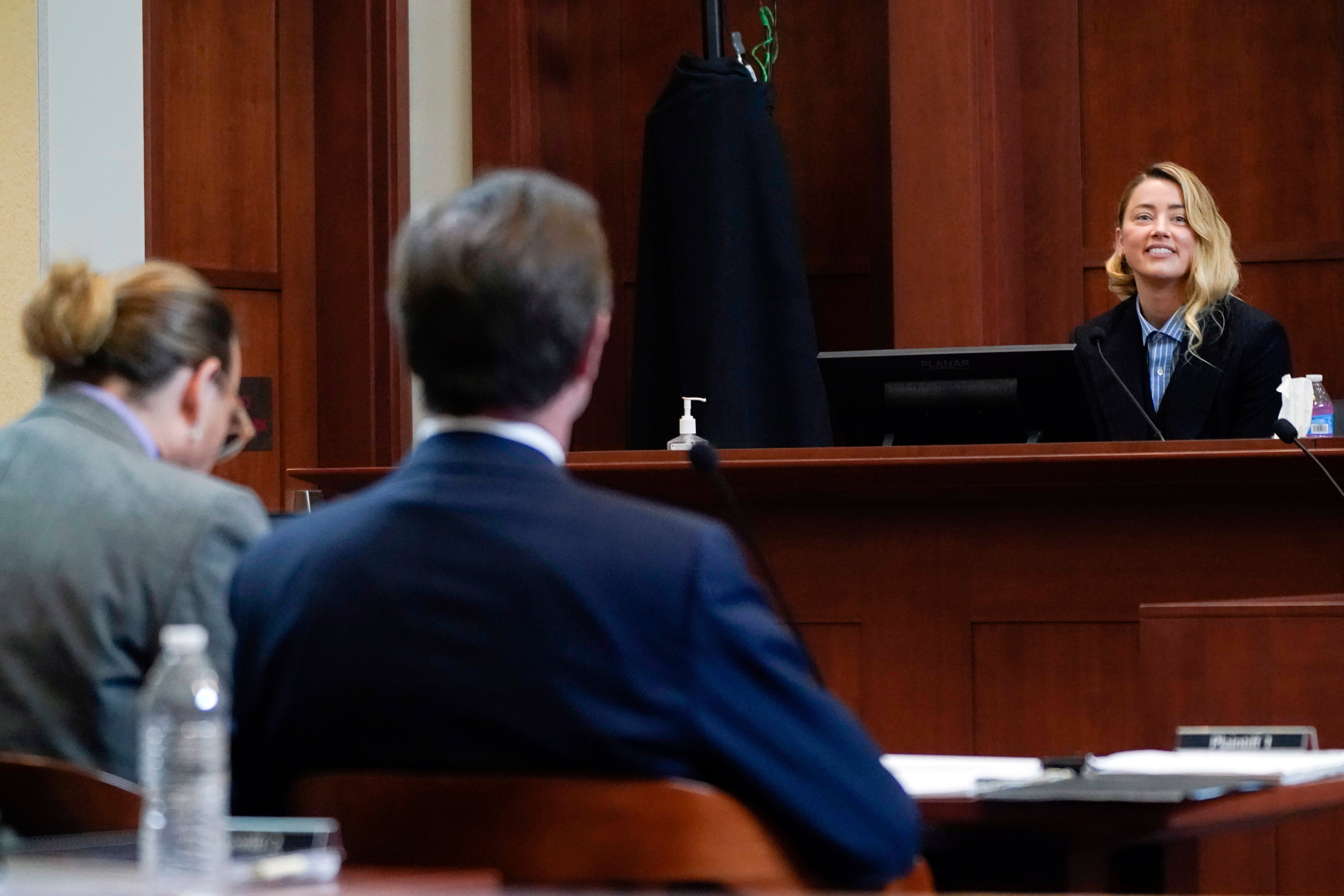 Amber Heard testifica mientras Johnny Depp, a la izquierda, escucha, en el Tribunal de Circuito del Condado de Fairfax, el miércoles 4 de mayo de 2022