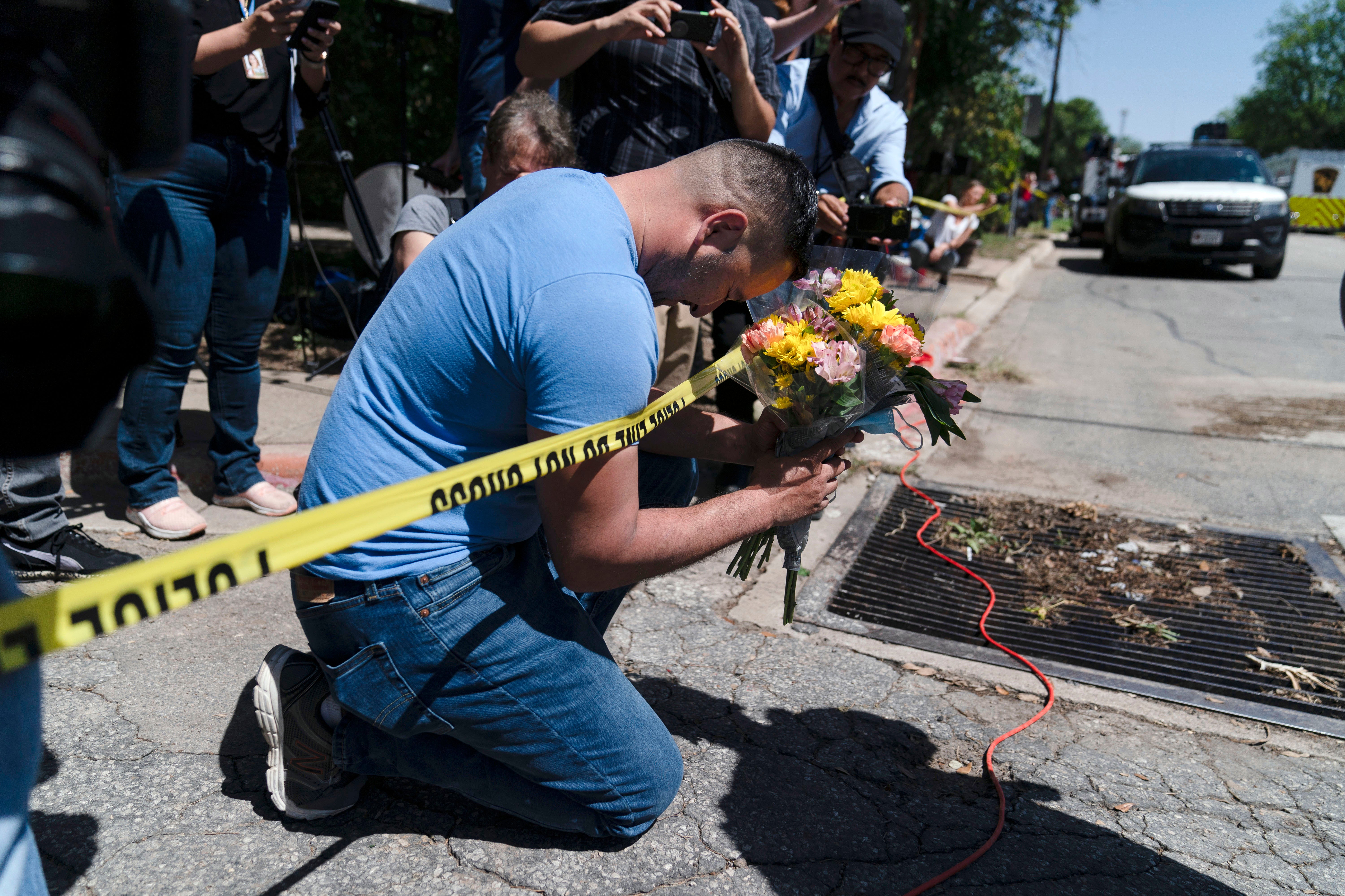 Joseph Ávila reza mientras sostiene flores en honor a las víctimas del tiroteo masivo del martes en la escuela primaria Robb en Uvalde, Texas