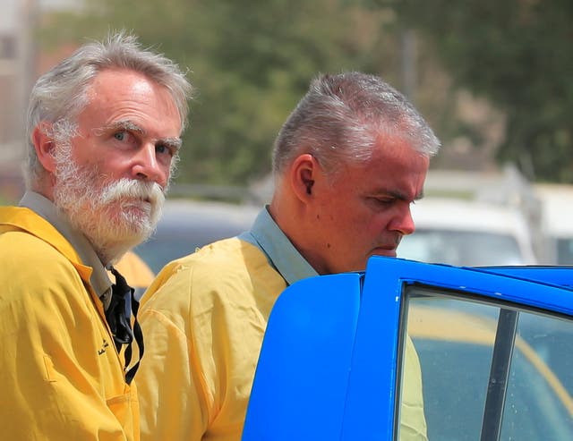 Jim Fitton (izq.) y Volker Waldmann son escoltados y esposados por policías iraquíes frente a un tribunal en Bagdad.