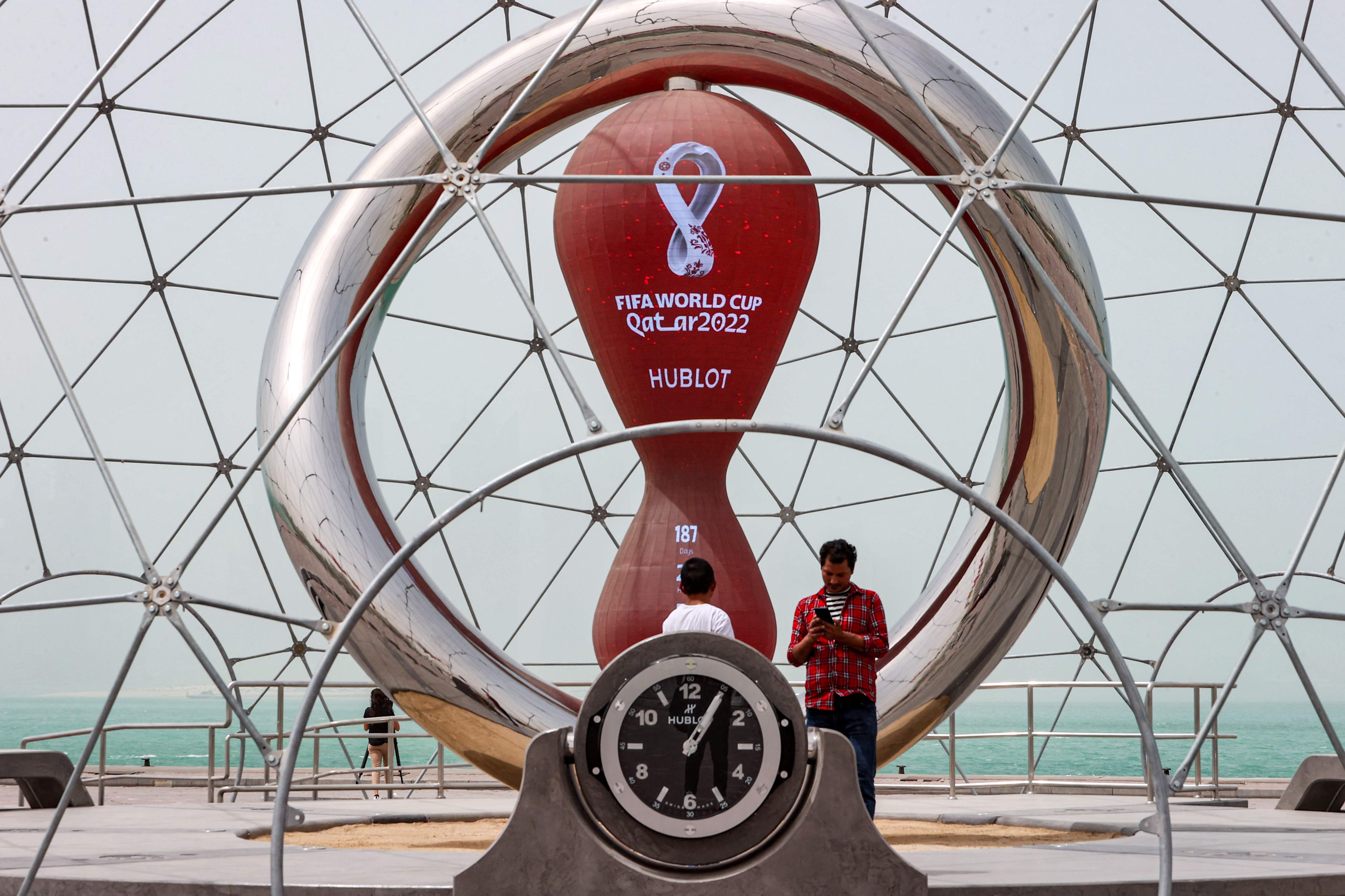People stand by the clock installation ticking the days to the start of the Qatar 2022 FIFA World Cup, along the waterfront in Qatar's capital Doha