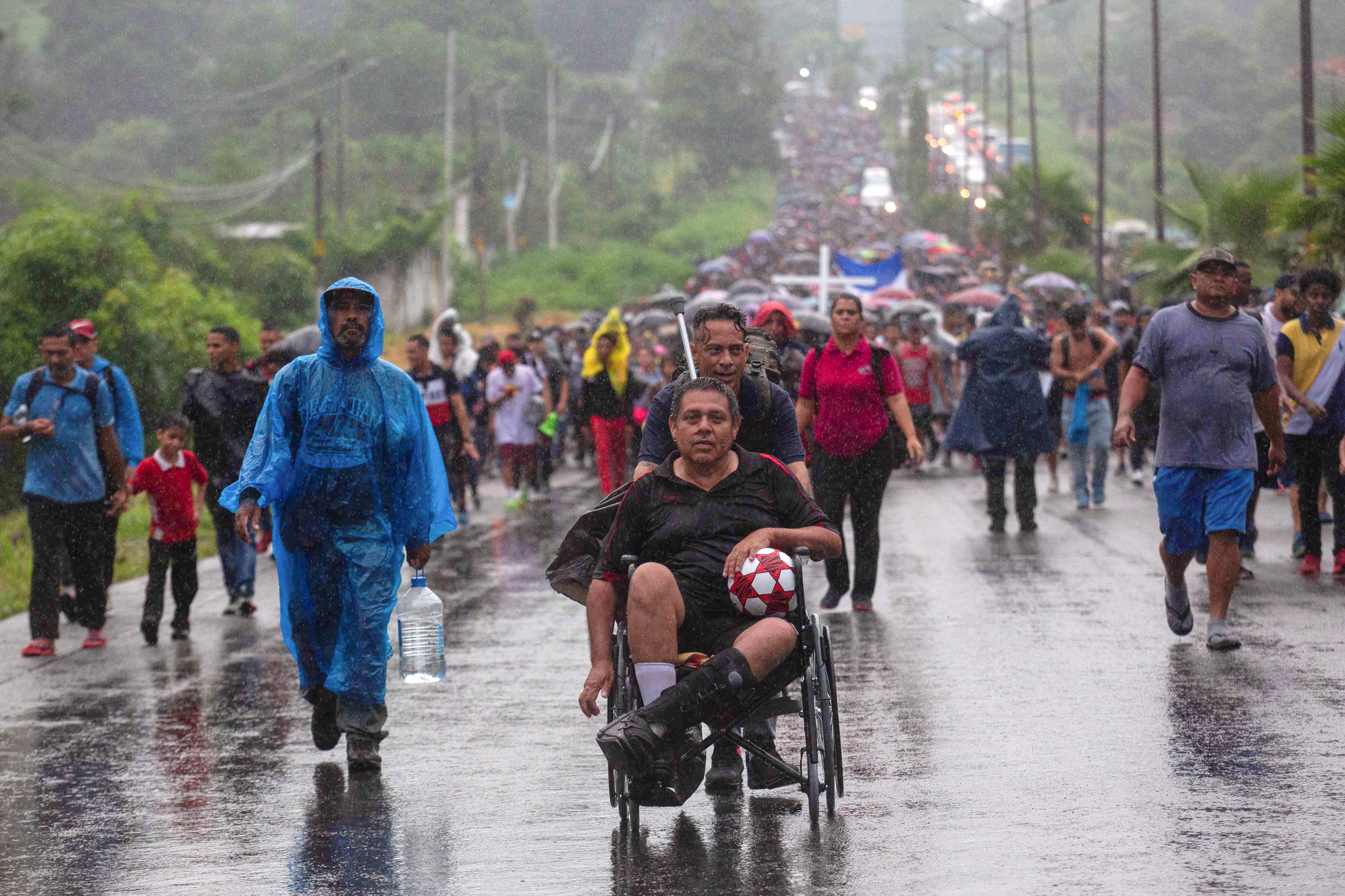 Un migrante en silla de ruedas sostiene un balón mientras es empujado por un compañero, durante una caravana para cruzar el país y llegar a la frontera con Estados Unidos, mientras los líderes regionales se reúnen en Los Ángeles para discutir la migración y otros temas, en Tapachula, México, el 6 de junio de 2022. REUTERS/Quetzalli Nicte-Ha