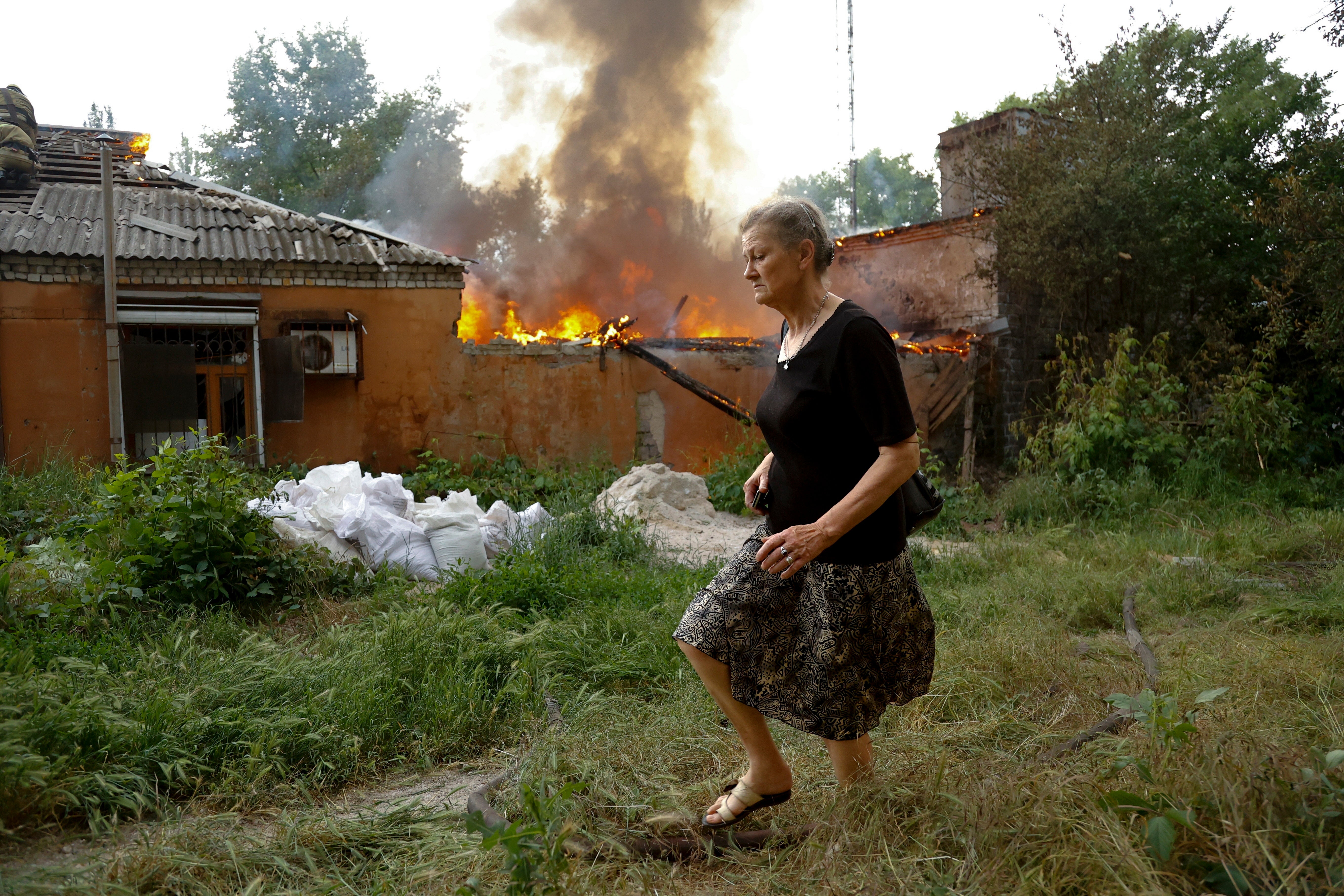 Una mujer huye de una casa en llamas tras un bombardeo en Donetsk