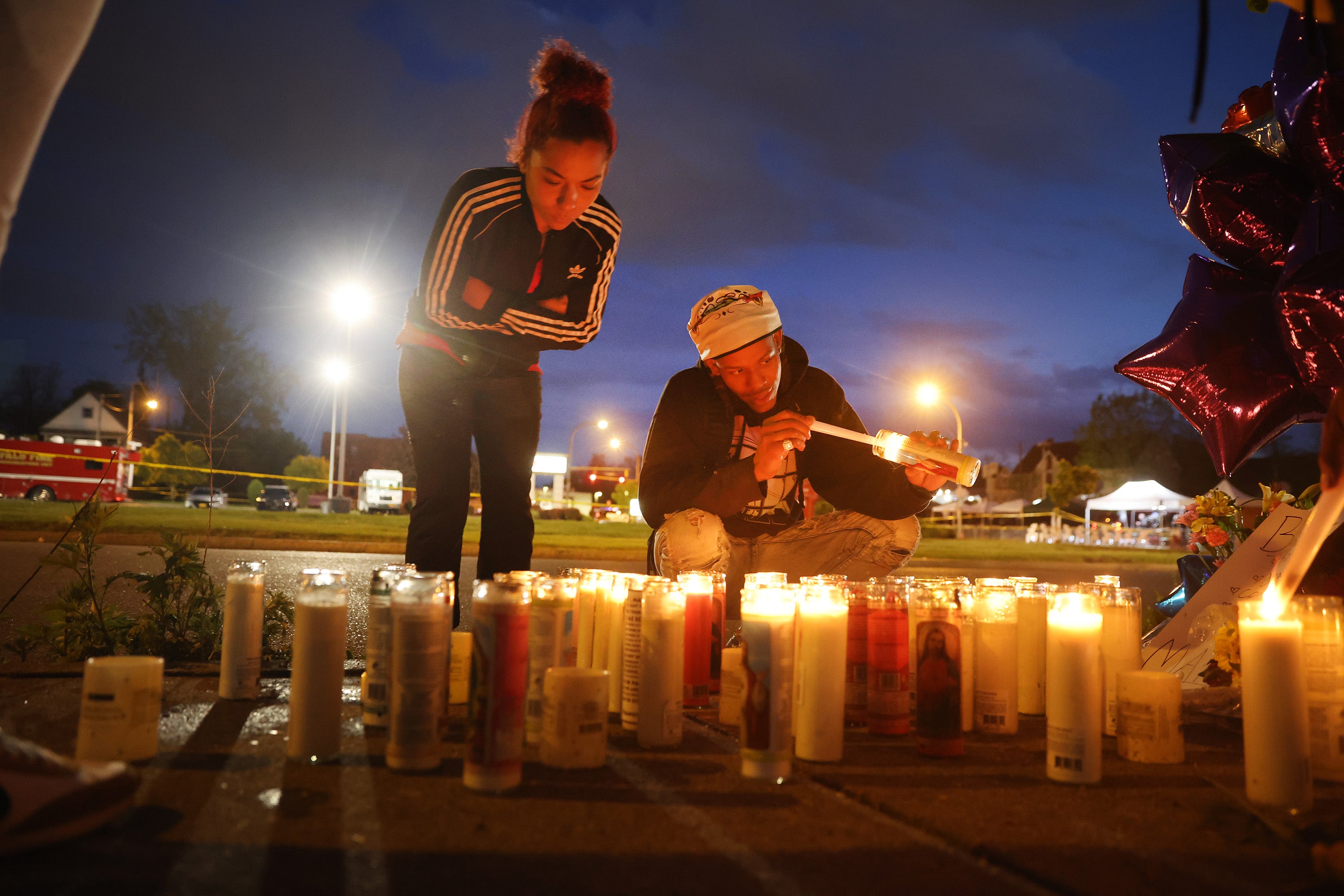Los dolientes encienden velas en un monumento improvisado fuera del supermercado Tops en Búfalo, Nueva York, donde 10 personas negras fueron asesinadas a tiros por un adolescente