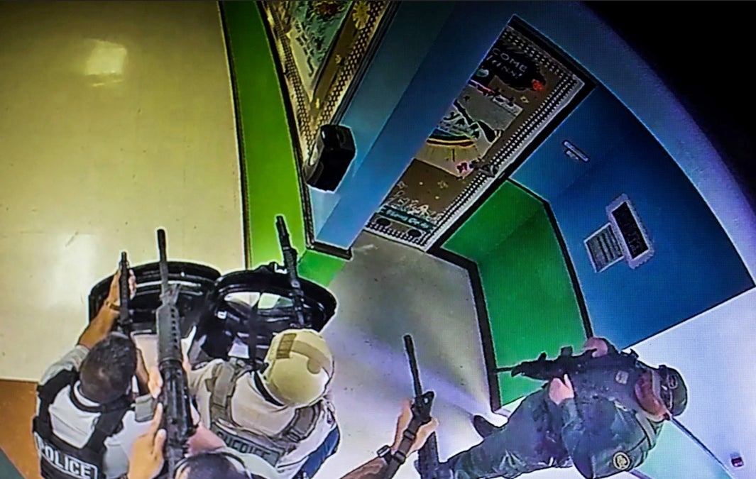 La foto, tomada de un vídeo de vigilancia del pasillo de la Escuela Primaria Robb, muestra a varios oficiales apuntando con rifles largos hacia las dos aulas contiguas