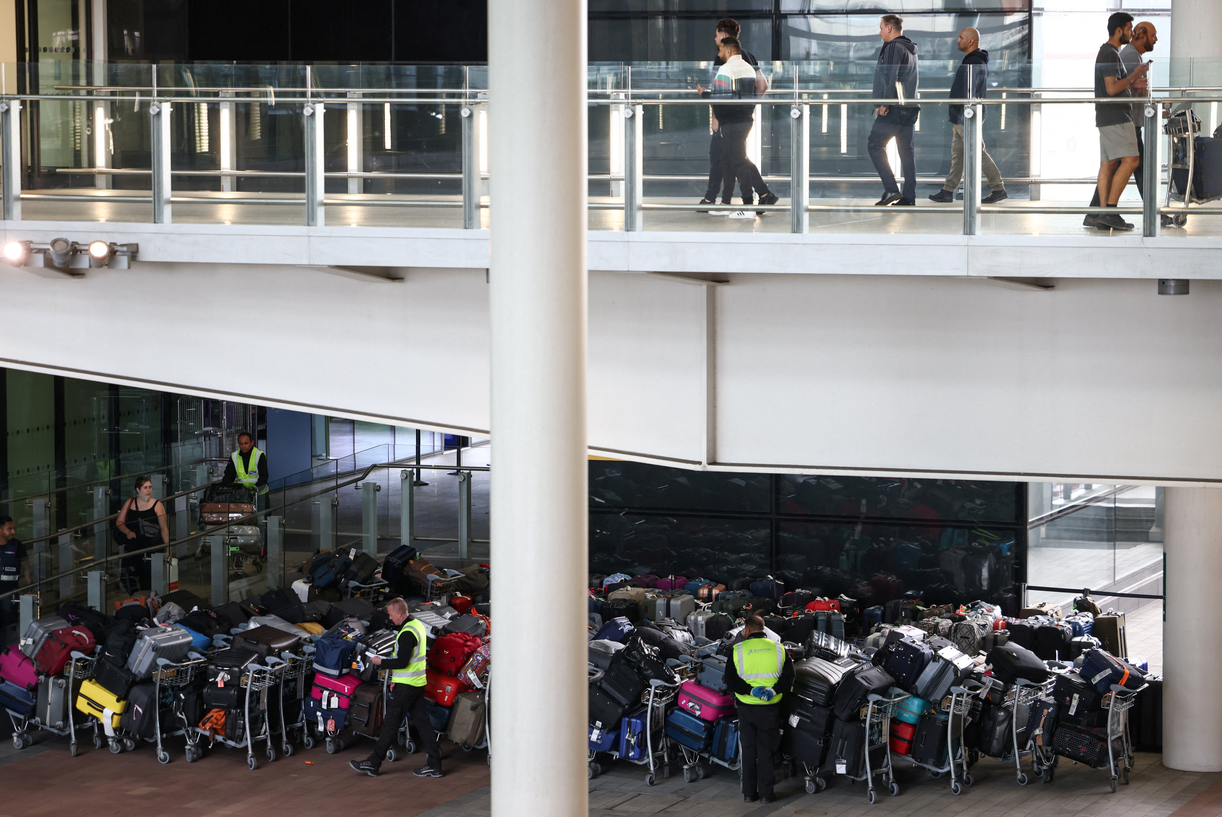 Trabajadores aeroportuarios junto a las colas de equipaje de los pasajeros dispuestas en el exterior de la Terminal 2 del aeropuerto de Heathrow