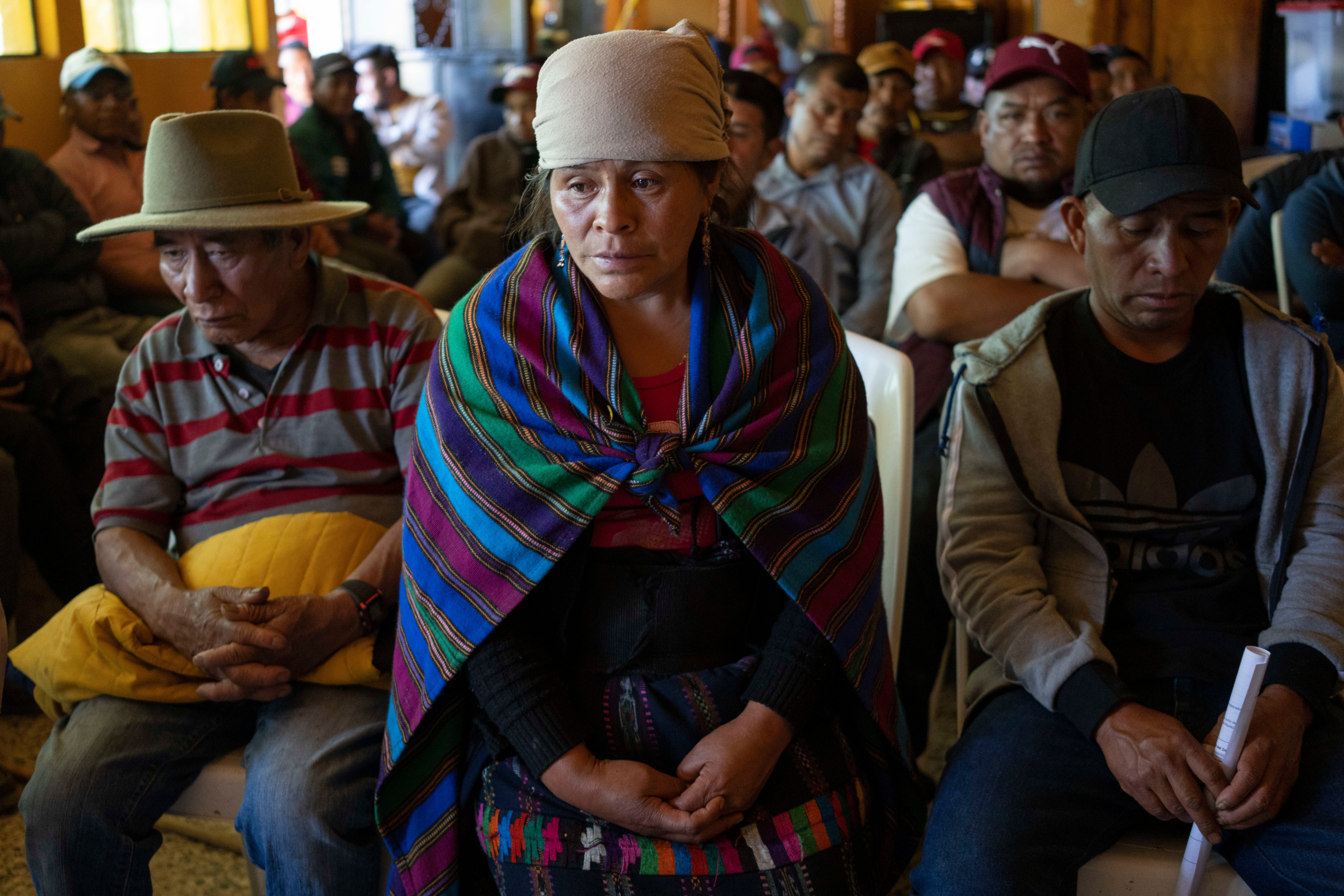 Magdalena Tepaz (cen) y Manuel de Jesus Tulul (der), padres de Wilmer Tulul, esperan el inicio de una reunión de la comunidad en Tzucubal, Guatemala