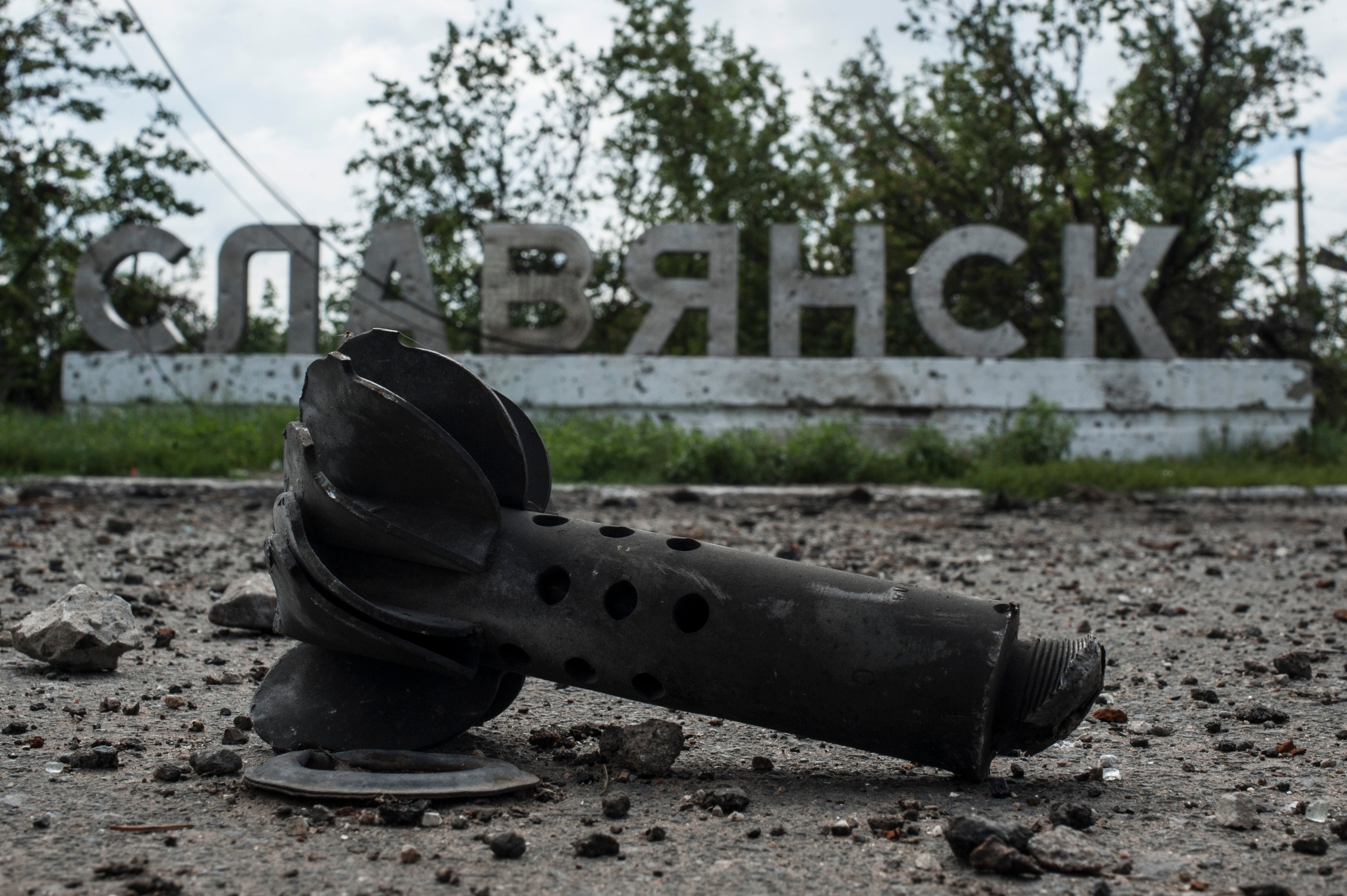 Parte de un mortero se ve ante un cartel donde pone “Slovyansk”, tras intensos combates entre combatientes prorrusos y ucranianos