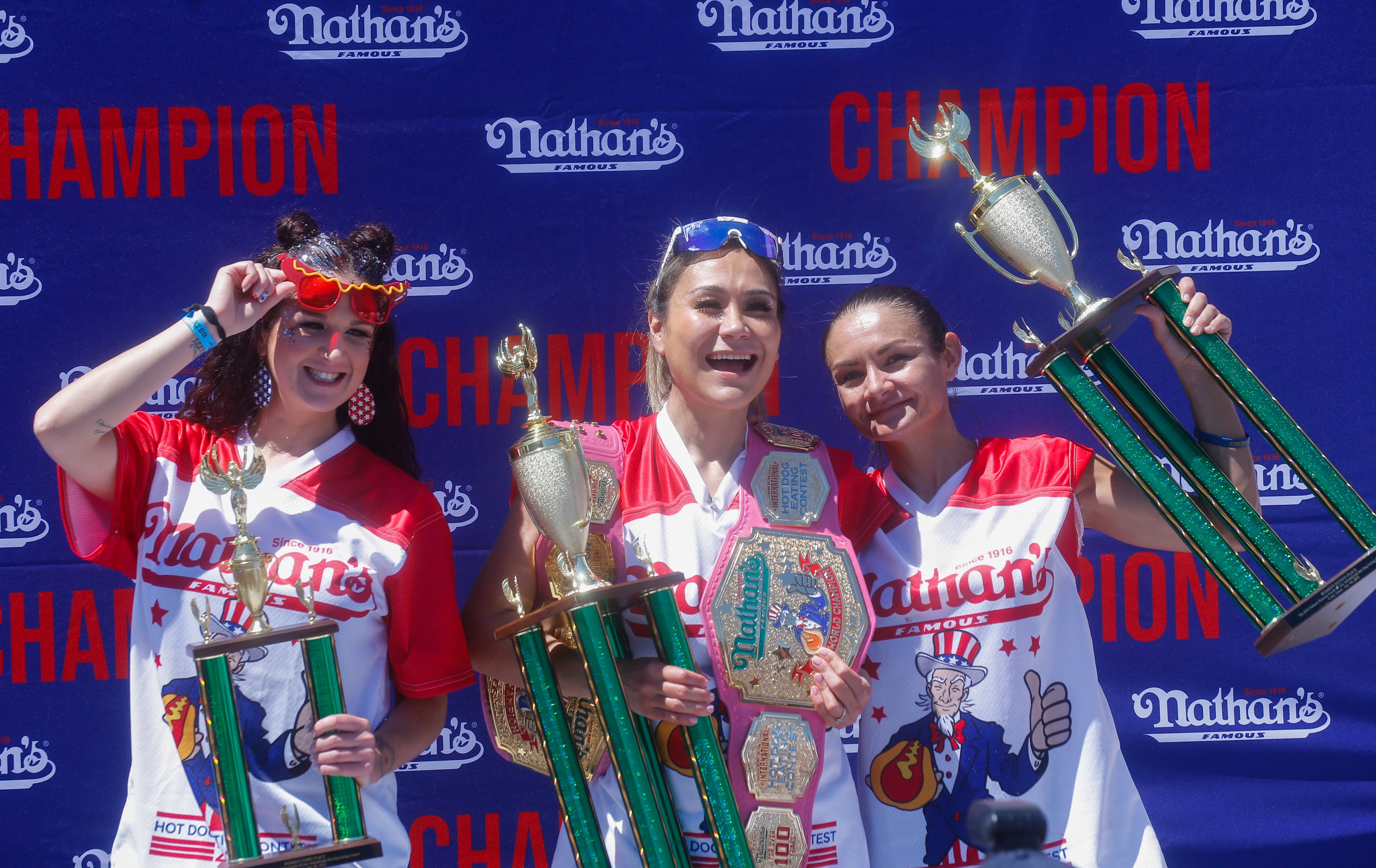 Miki Sudo (centro) posa después de ganar el primer lugar al haber comido 40 hot dogs en 10 minutos, durante el Concurso Femenino Internacional de Hot Dogs de Nathan’s Famous del 4 de julio de 2022