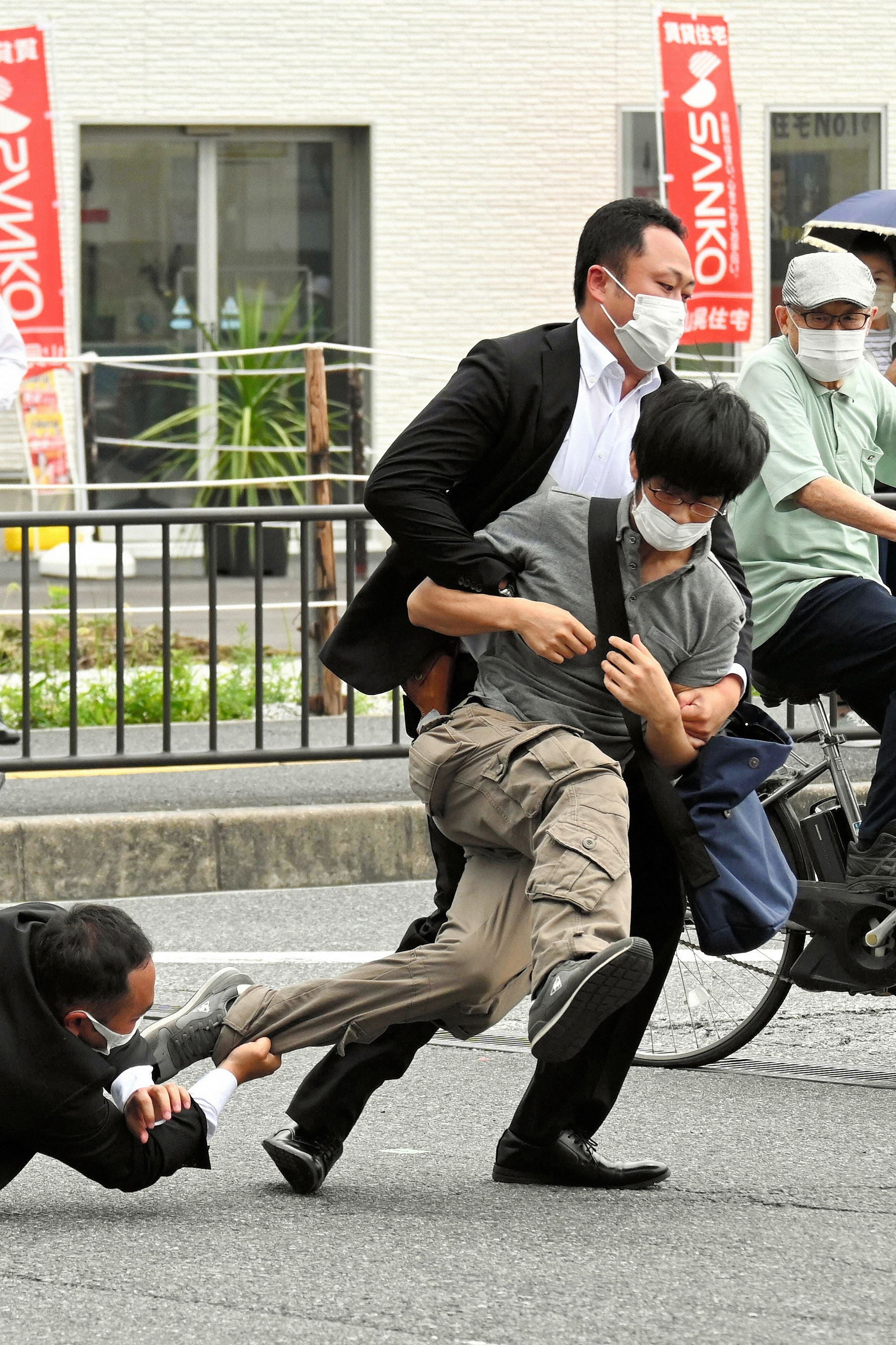 Esta imagen provista por el periódico Asahi Shimbun muestra al sospechoso de asesinar a Shinzo Abe ser derribado por agentes de policía